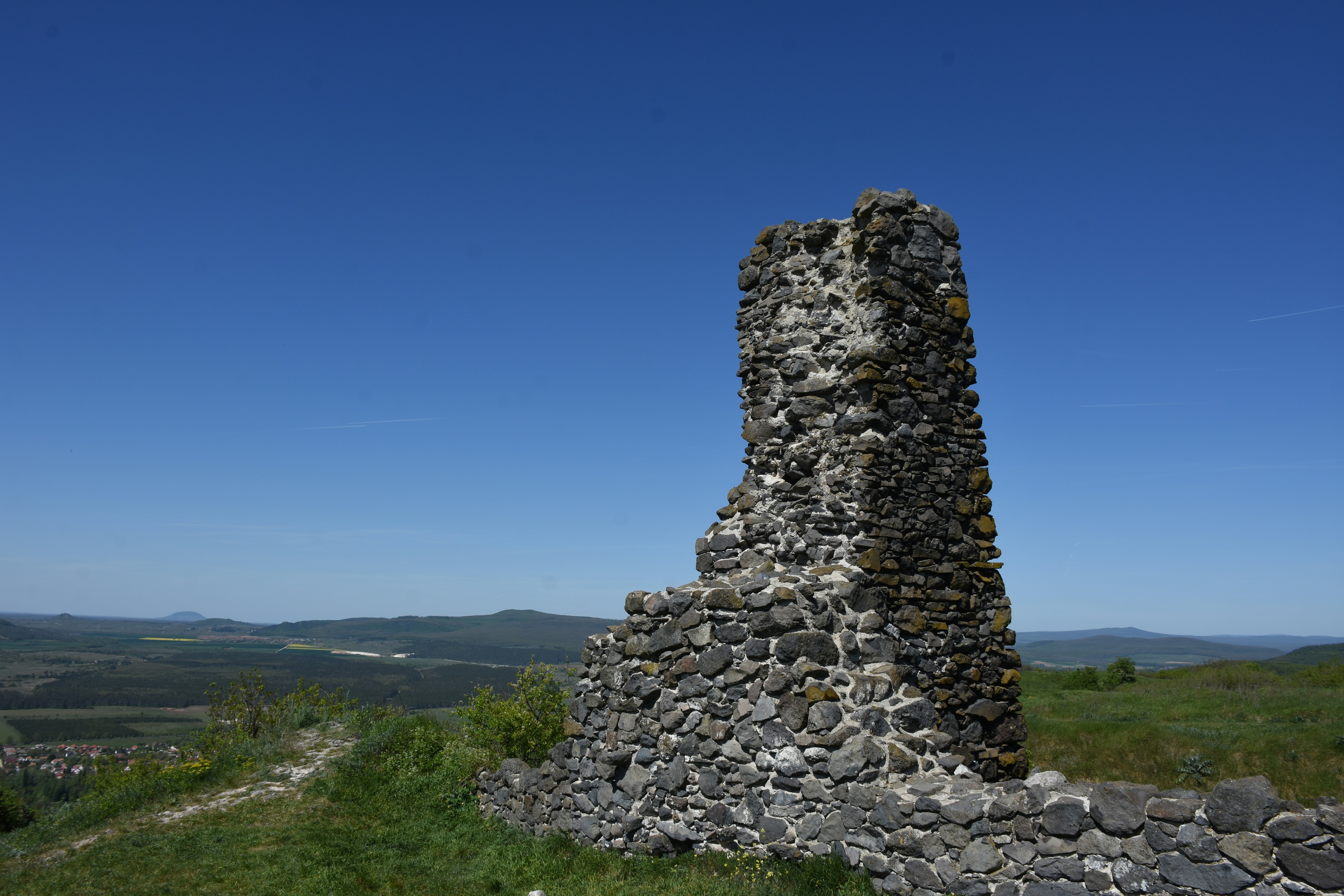 Stone ruins of a castle on a grassy hill.