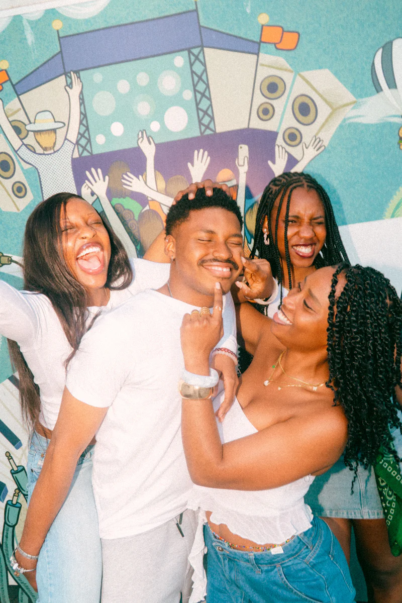 Four friends laughing together in front of a colorful mural