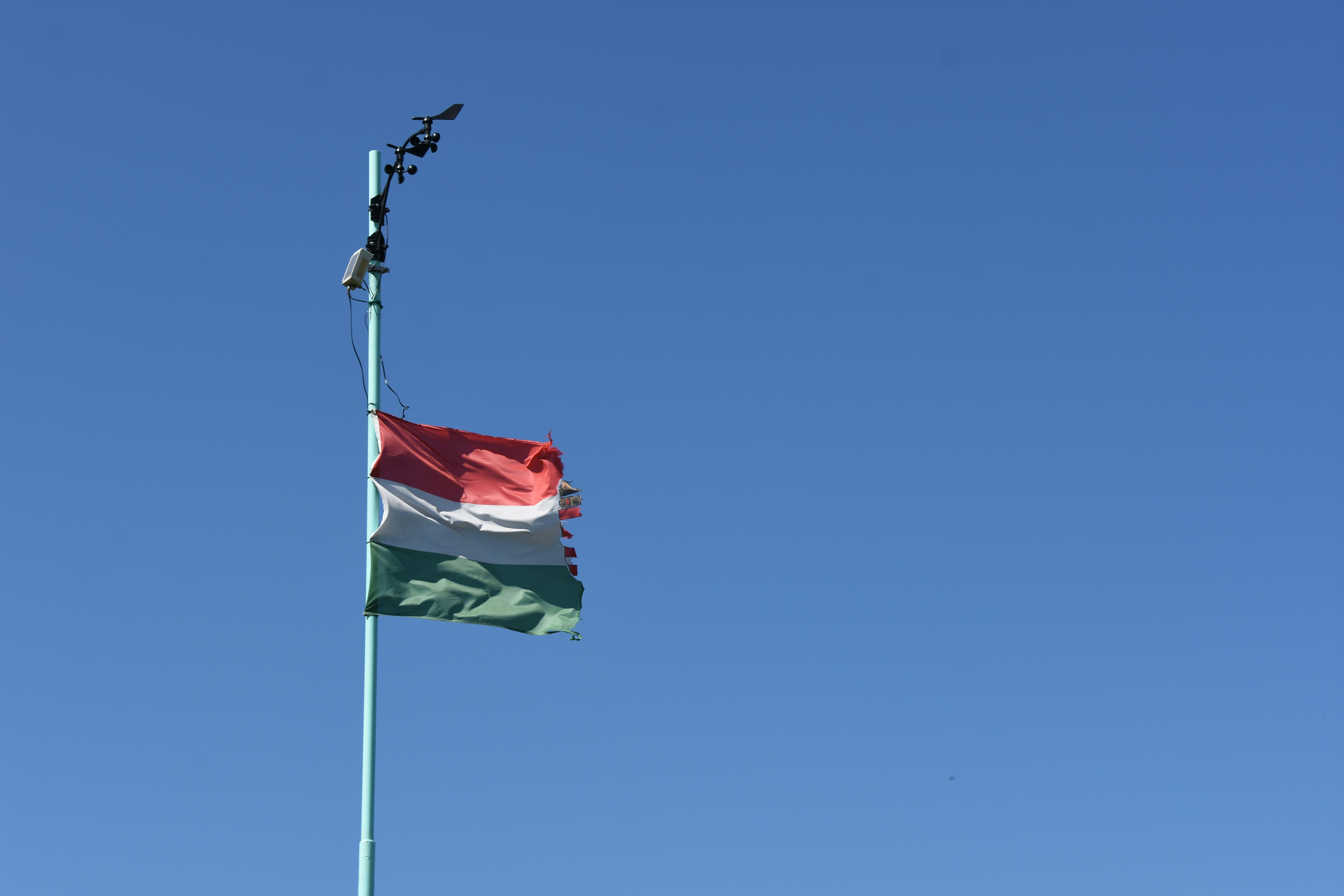 A flag with red, white, and green stripes flies.