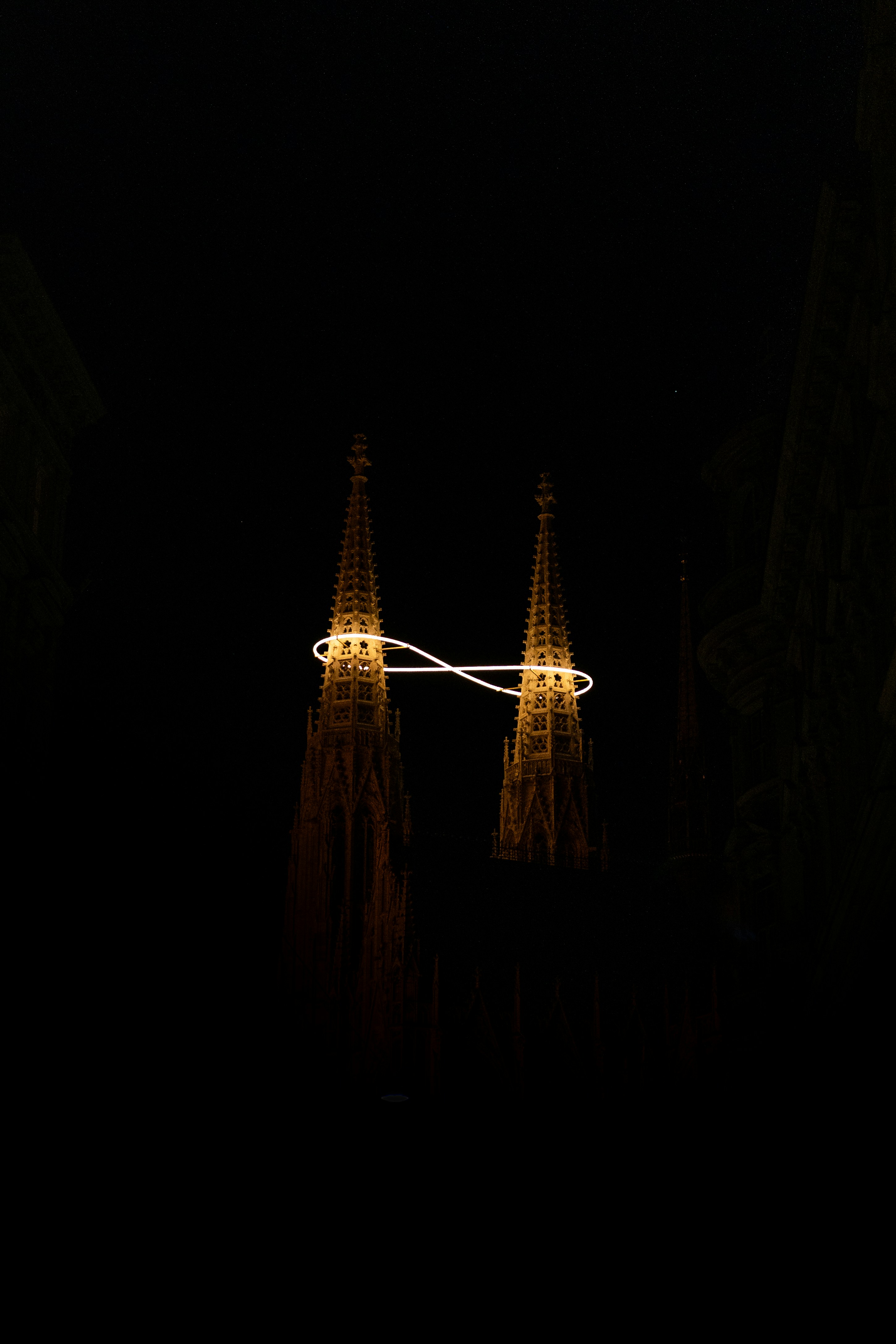 Two illuminated gothic spires connected by a light ring.