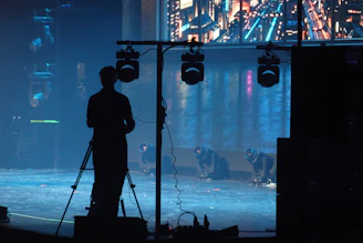 A person filming on a tripod on a stage.