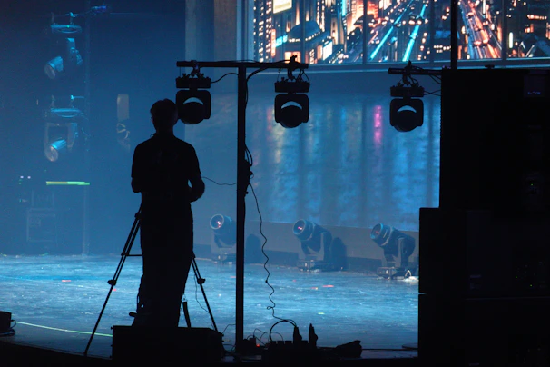 A person filming on a tripod on a stage.