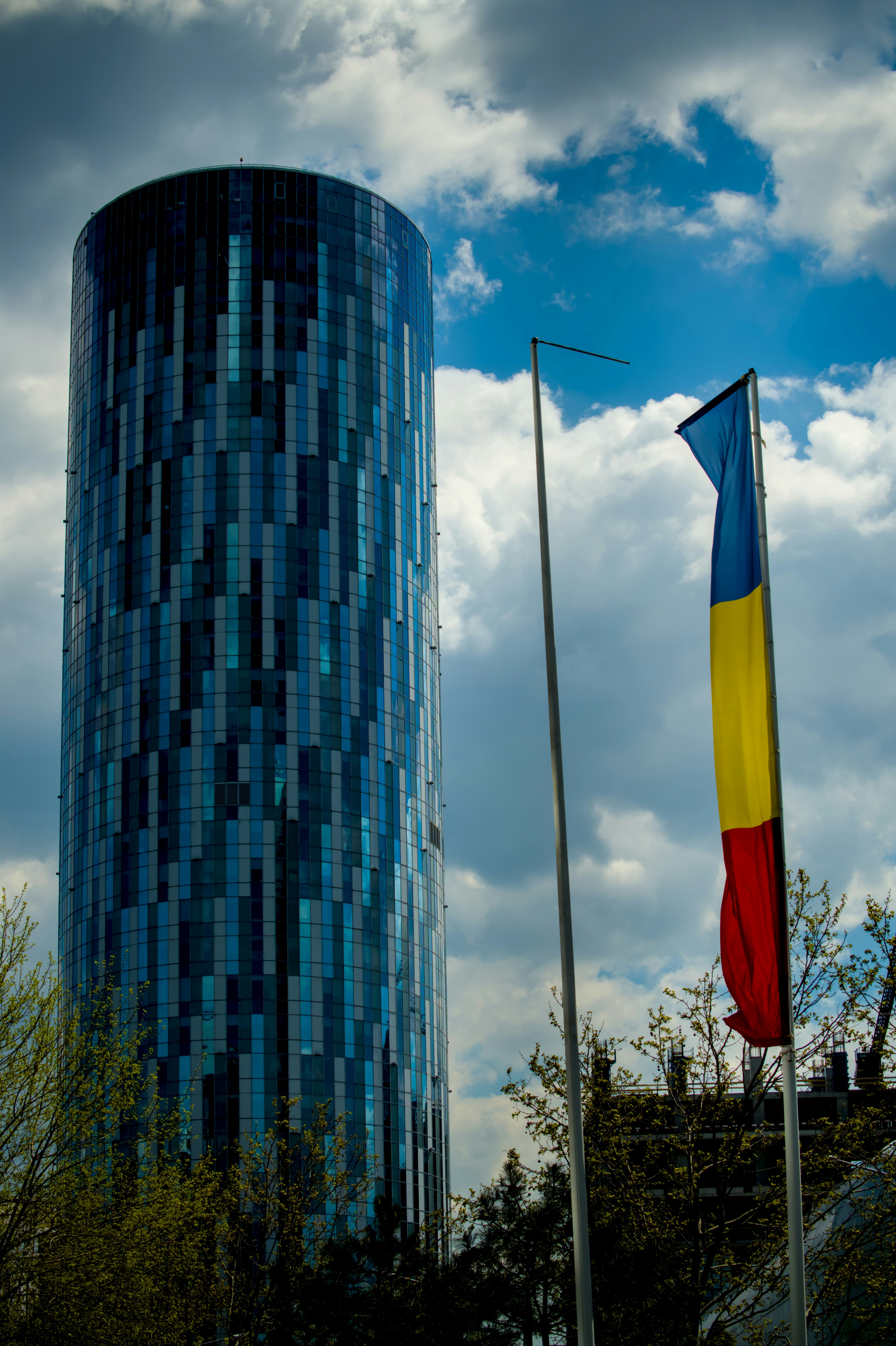 Gratte-ciel moderne à côté du drapeau roumain et des arbres