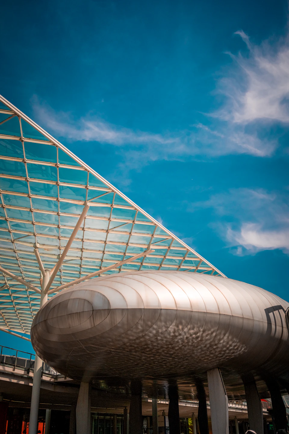 Large modern building with curved roof and glass facade reflects surrounding environment clearly outside