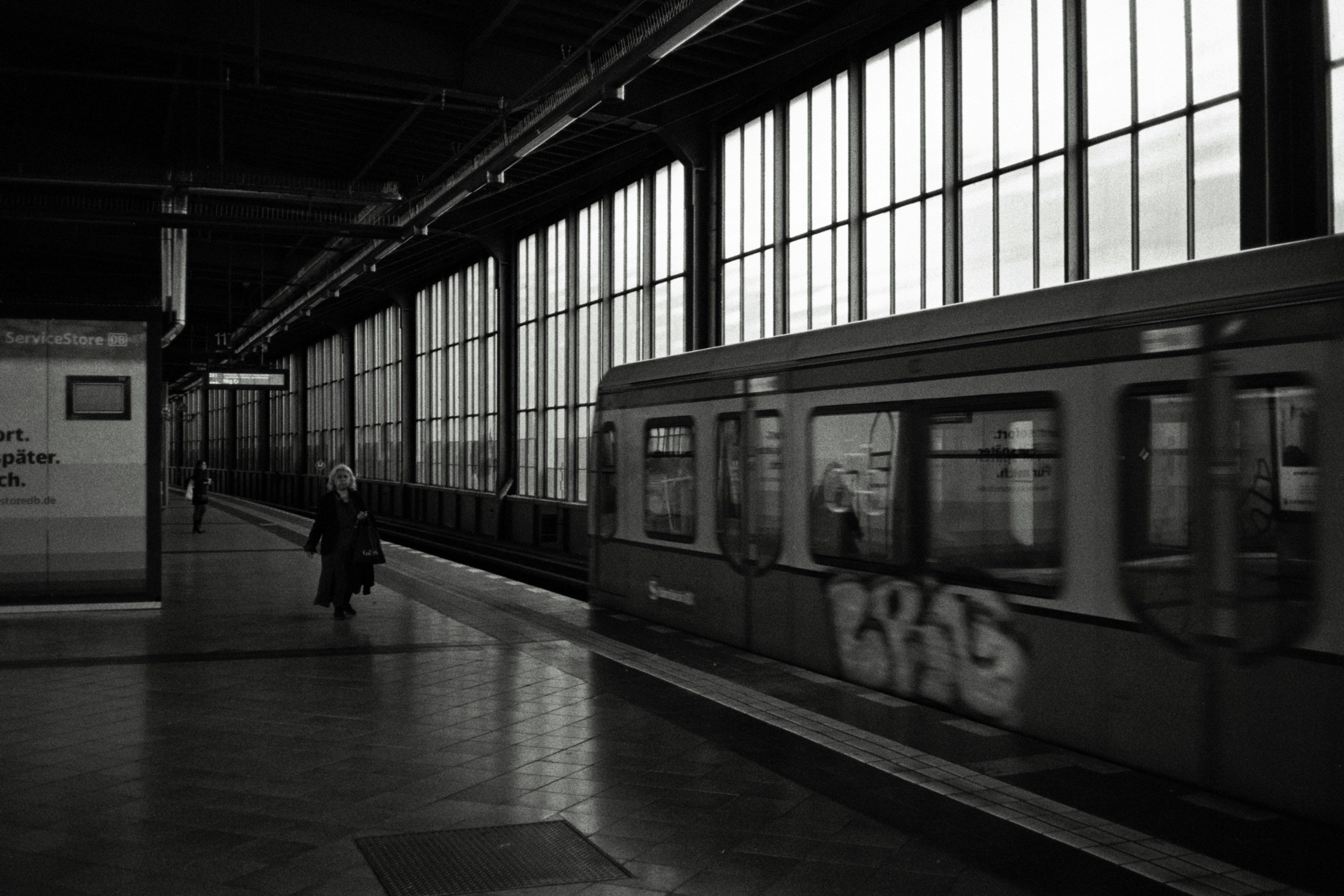 Treno che arriva a una stazione della metropolitana con grandi finestre.