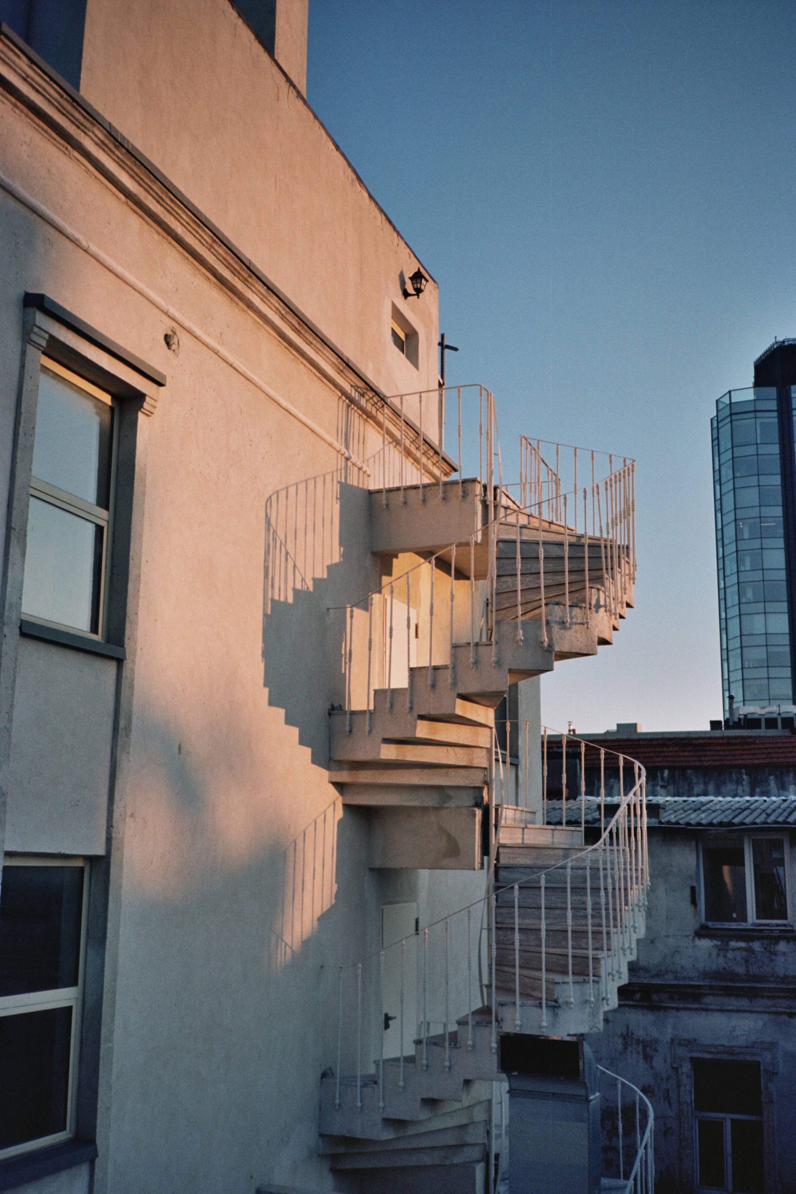 Scala a chiocciola bianca all'esterno dell'edificio al tramonto.
