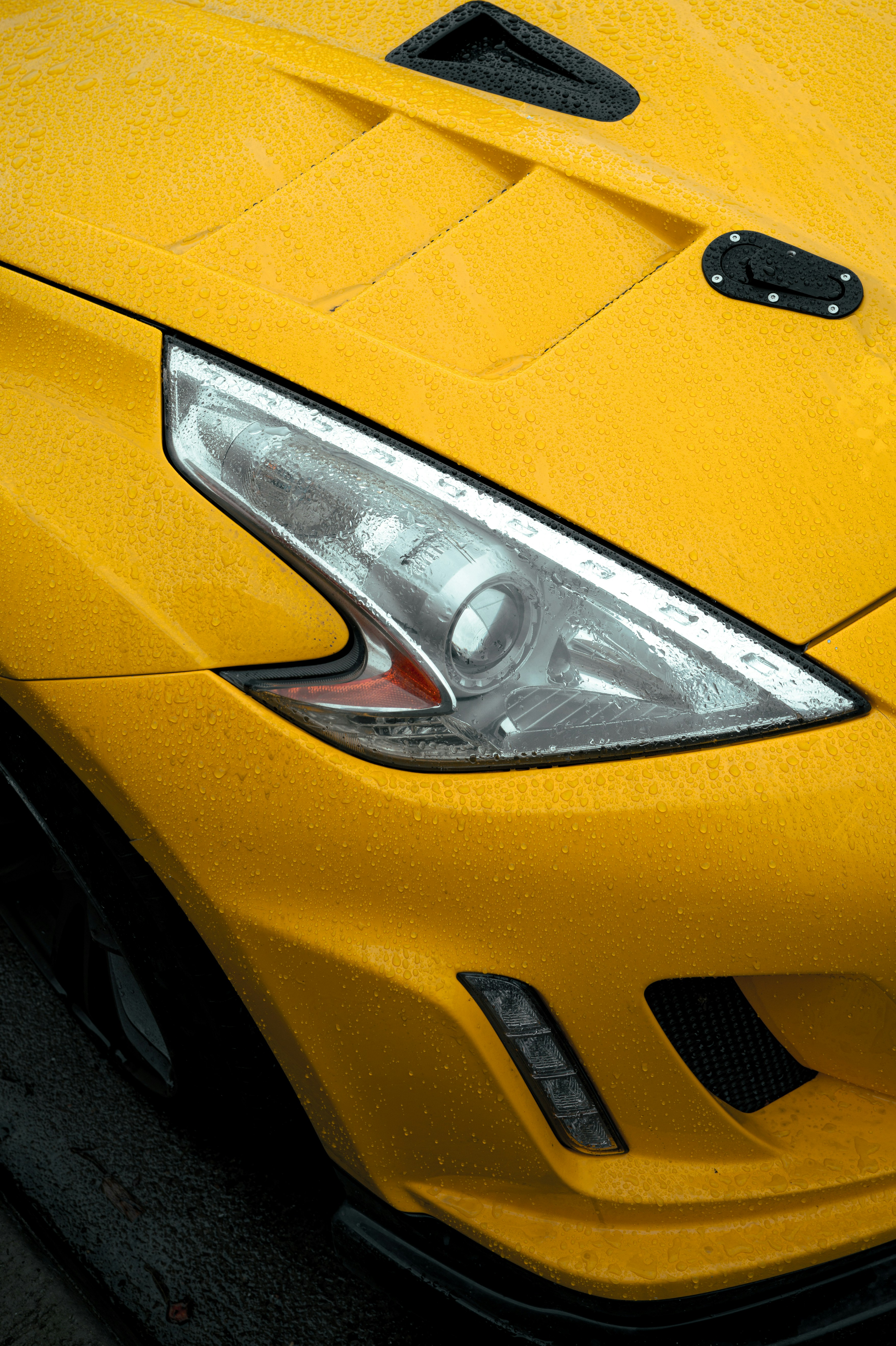 Close de um carro esportivo amarelo na chuva