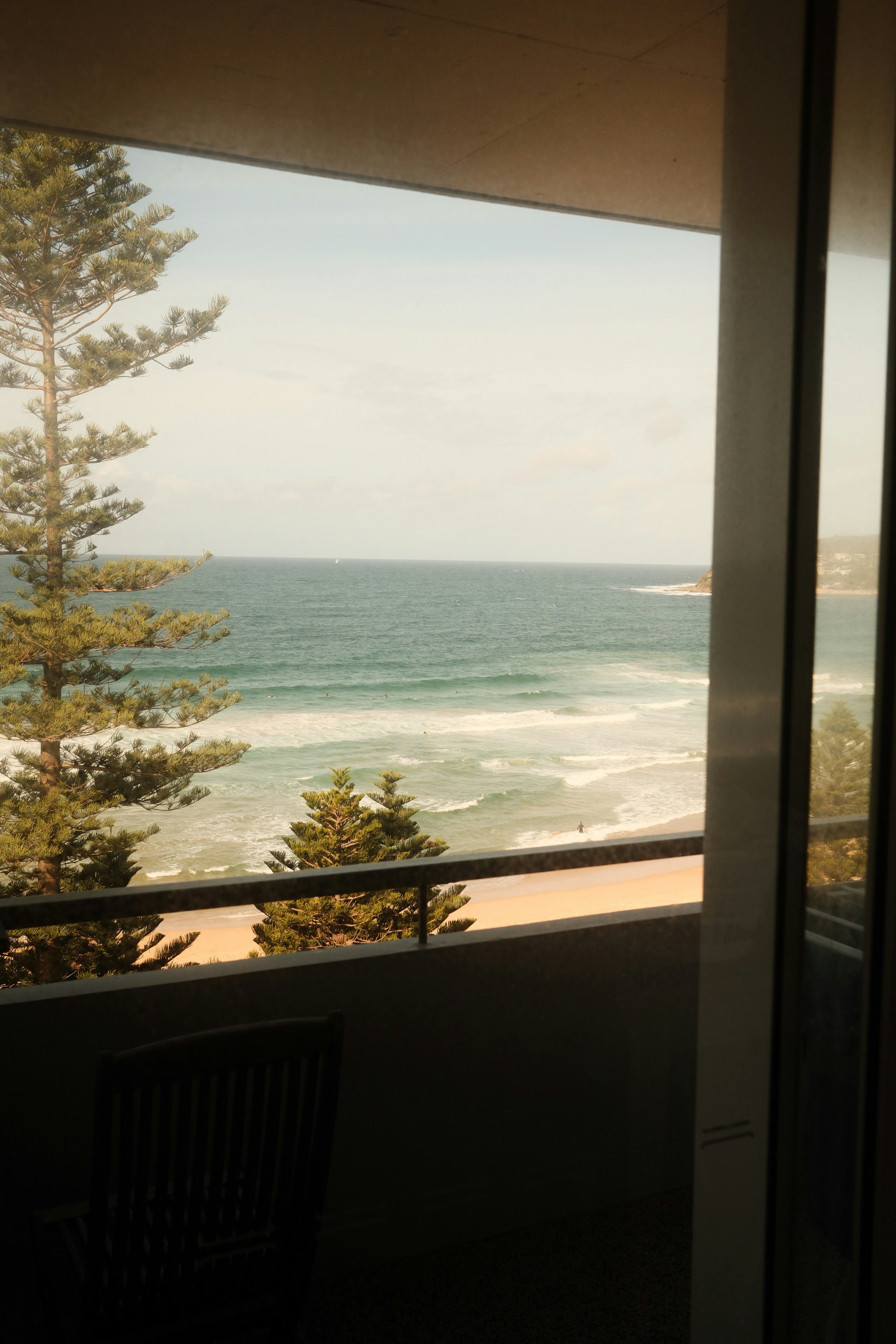 Ocean waves crash on a sandy beach viewed from balcony.