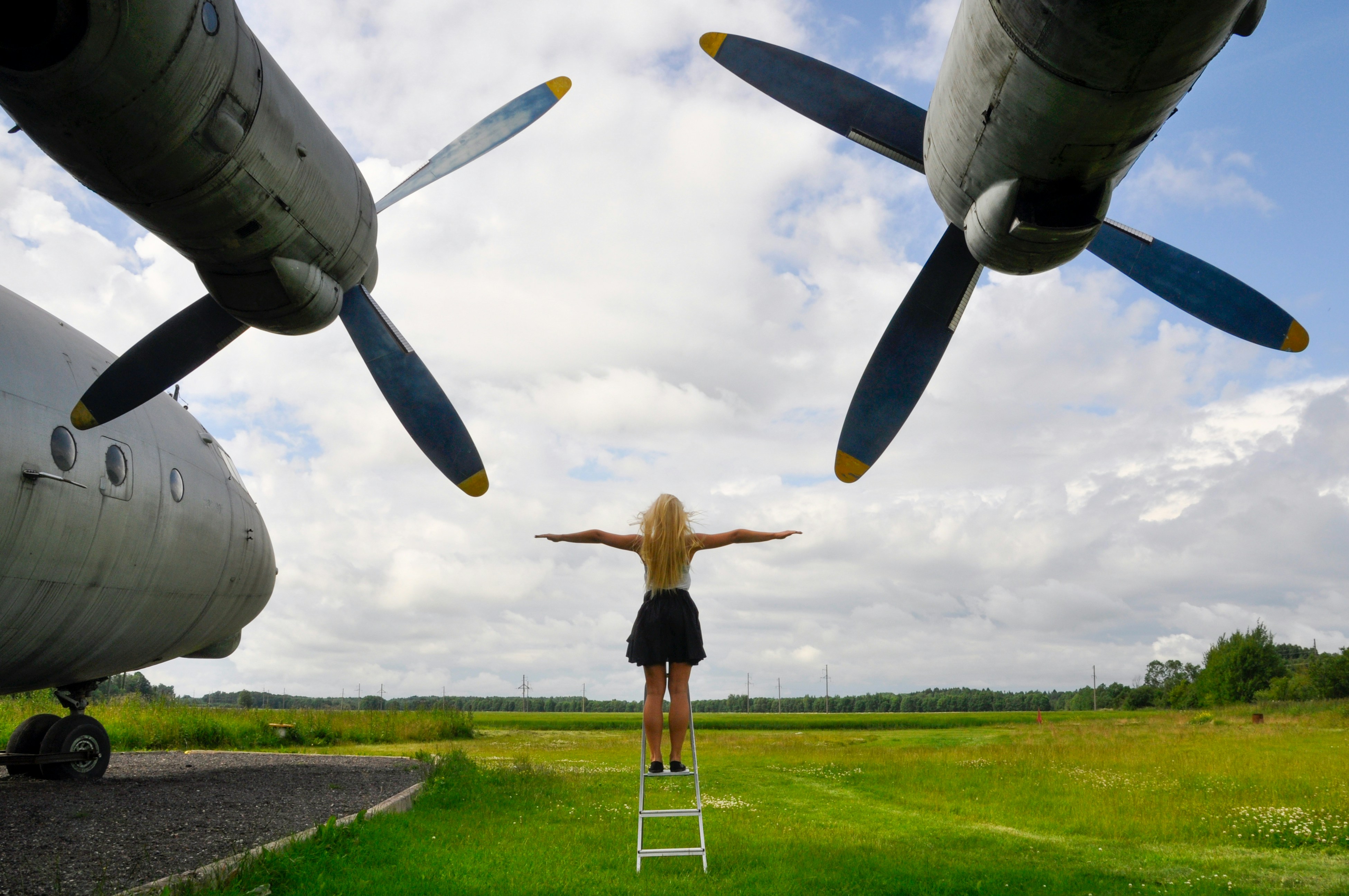 Woman on ladder between airplane propellers