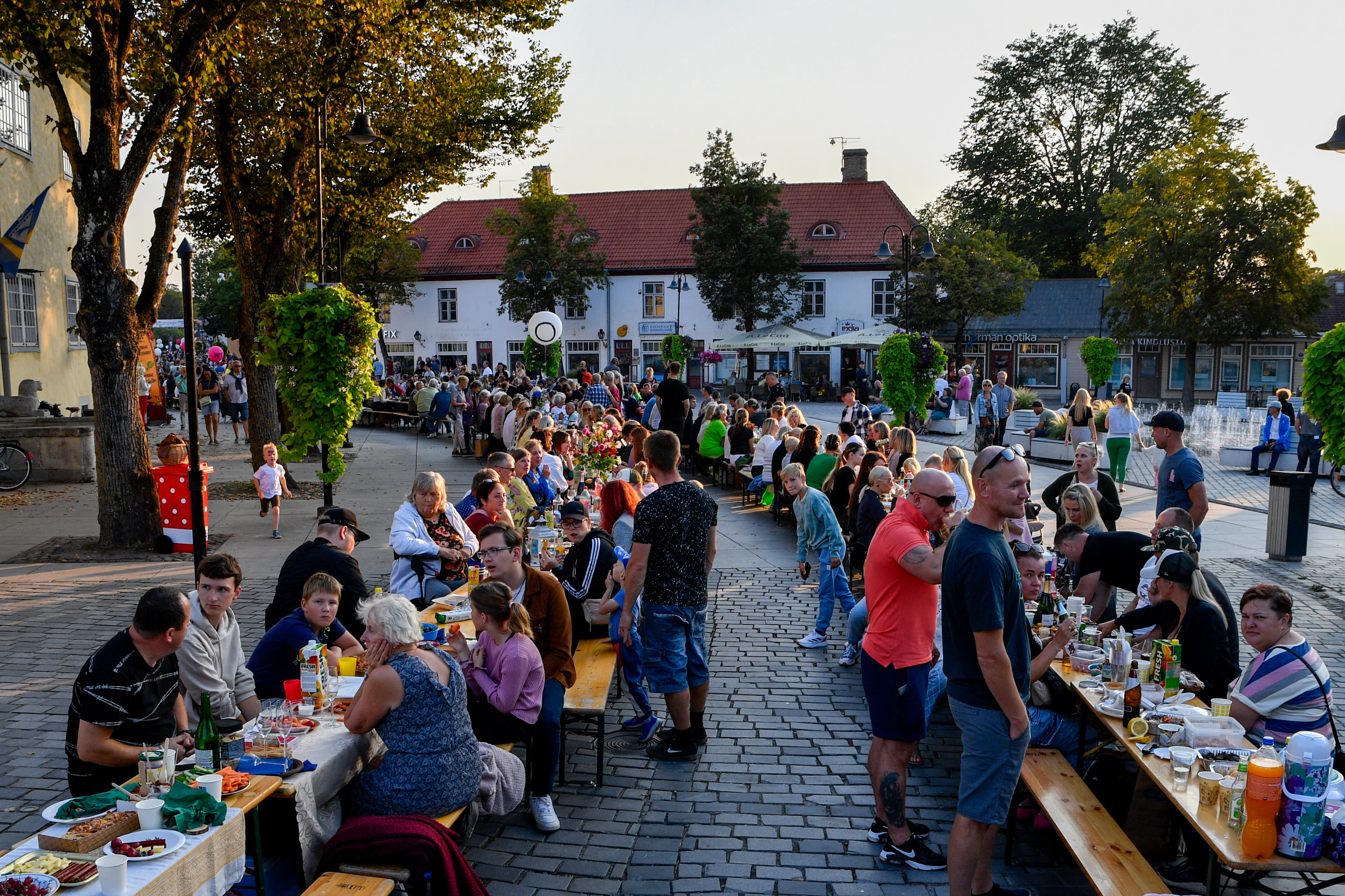 Neighbors gathered at long tables outdoors at dusk