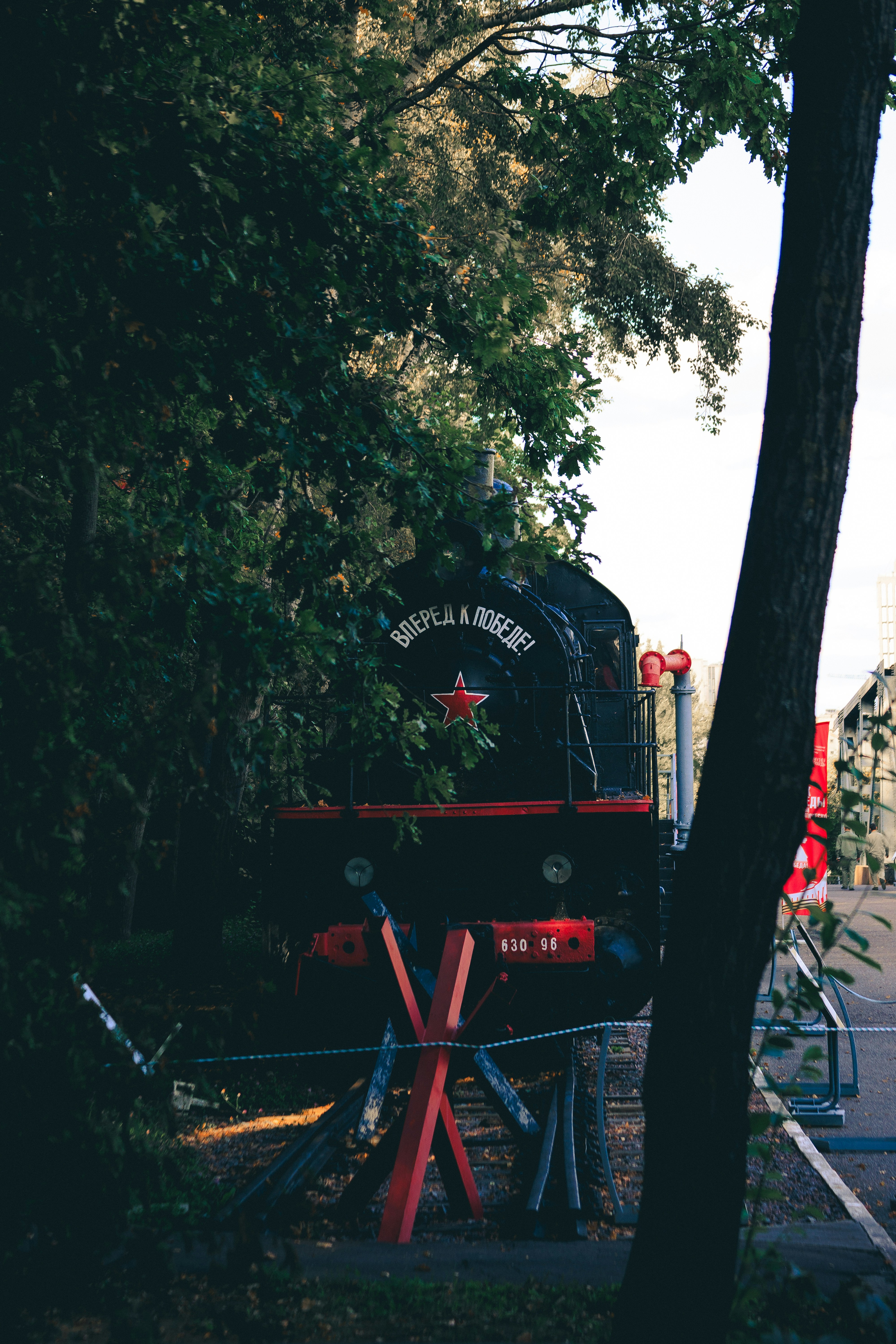 Locomotora negra con estrella roja y texto entre los árboles.
