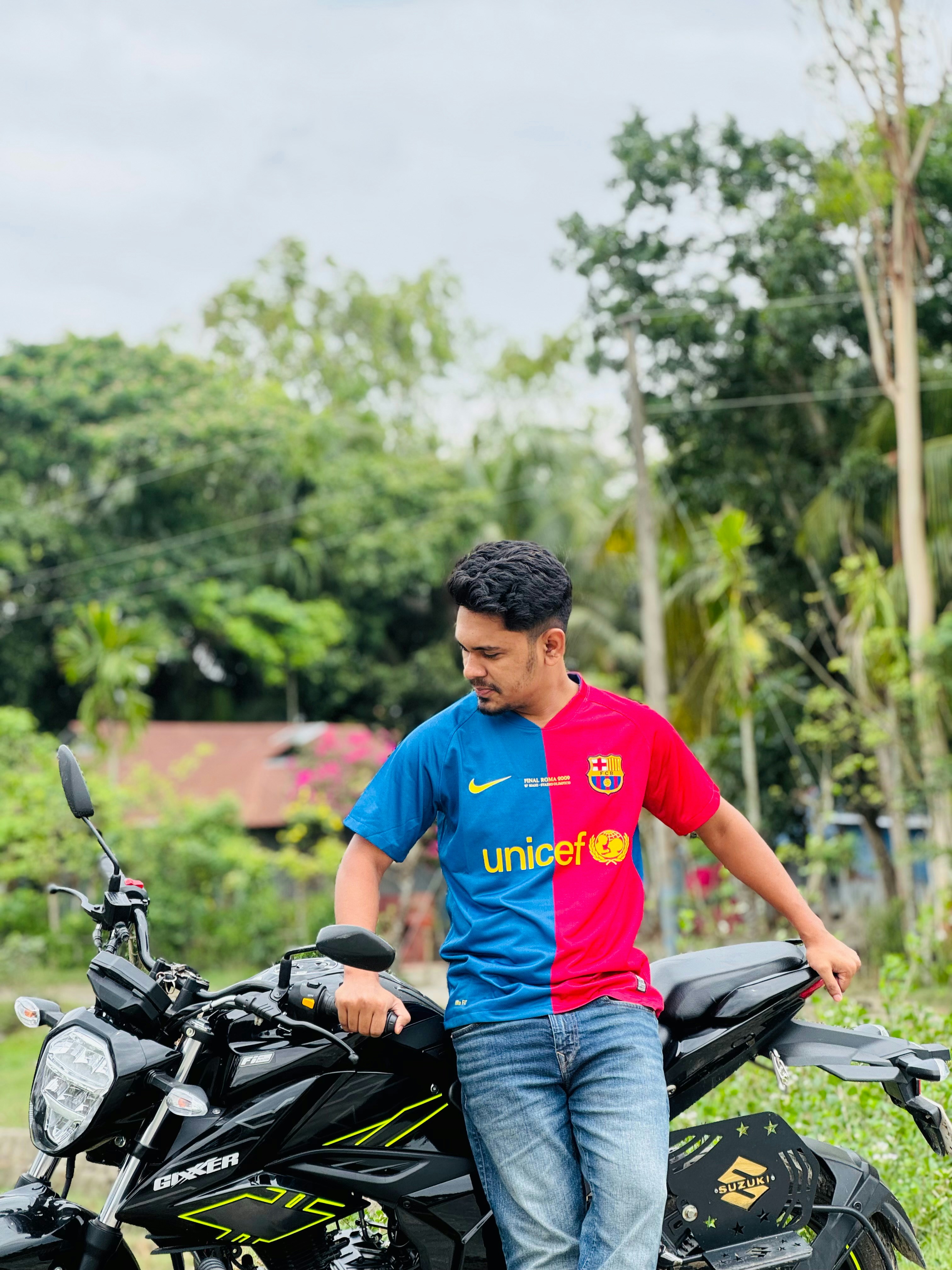 Pria berbaju biru dan merah bersandar di sepeda motor.