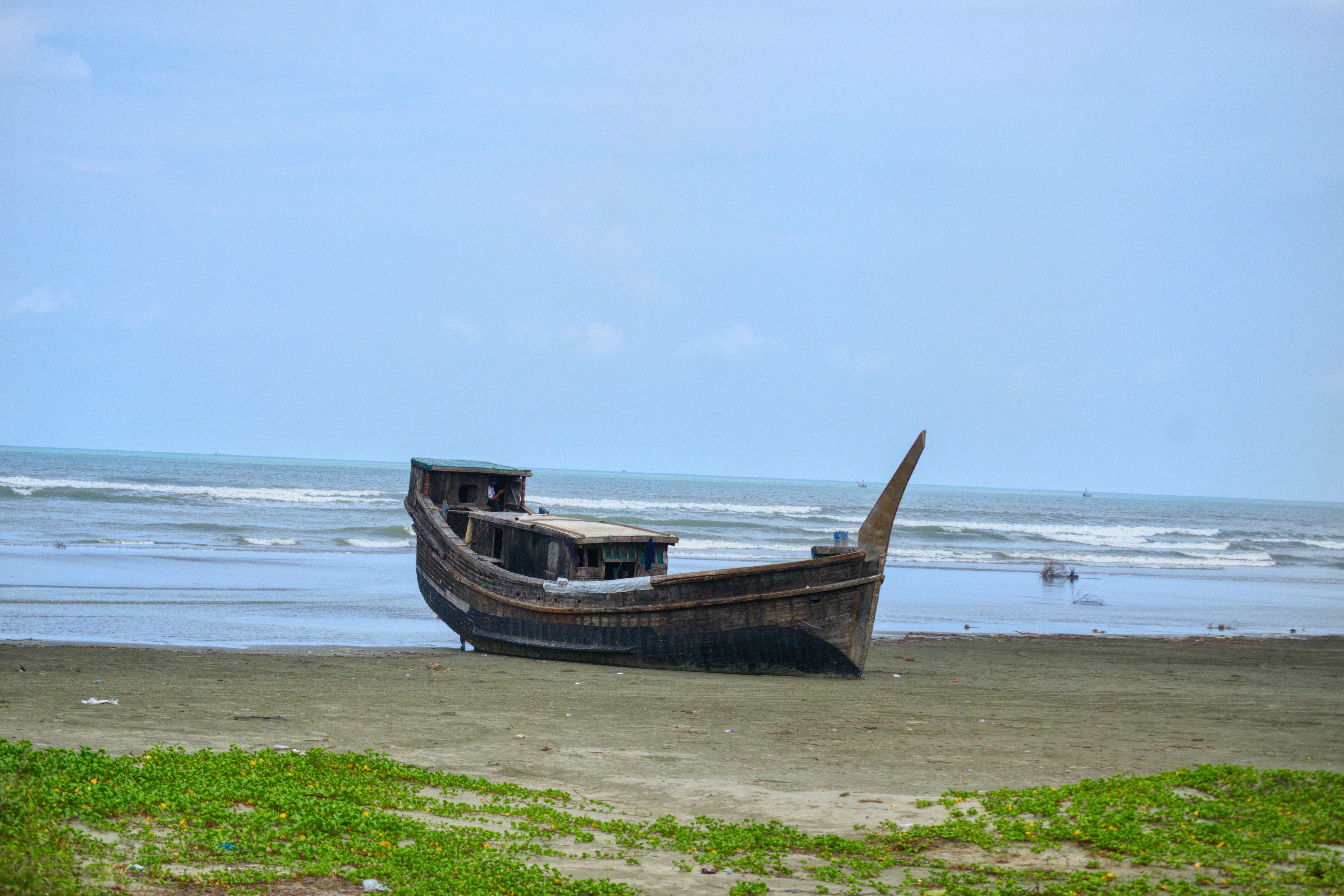 An old wooden boat rests on a sandy beach