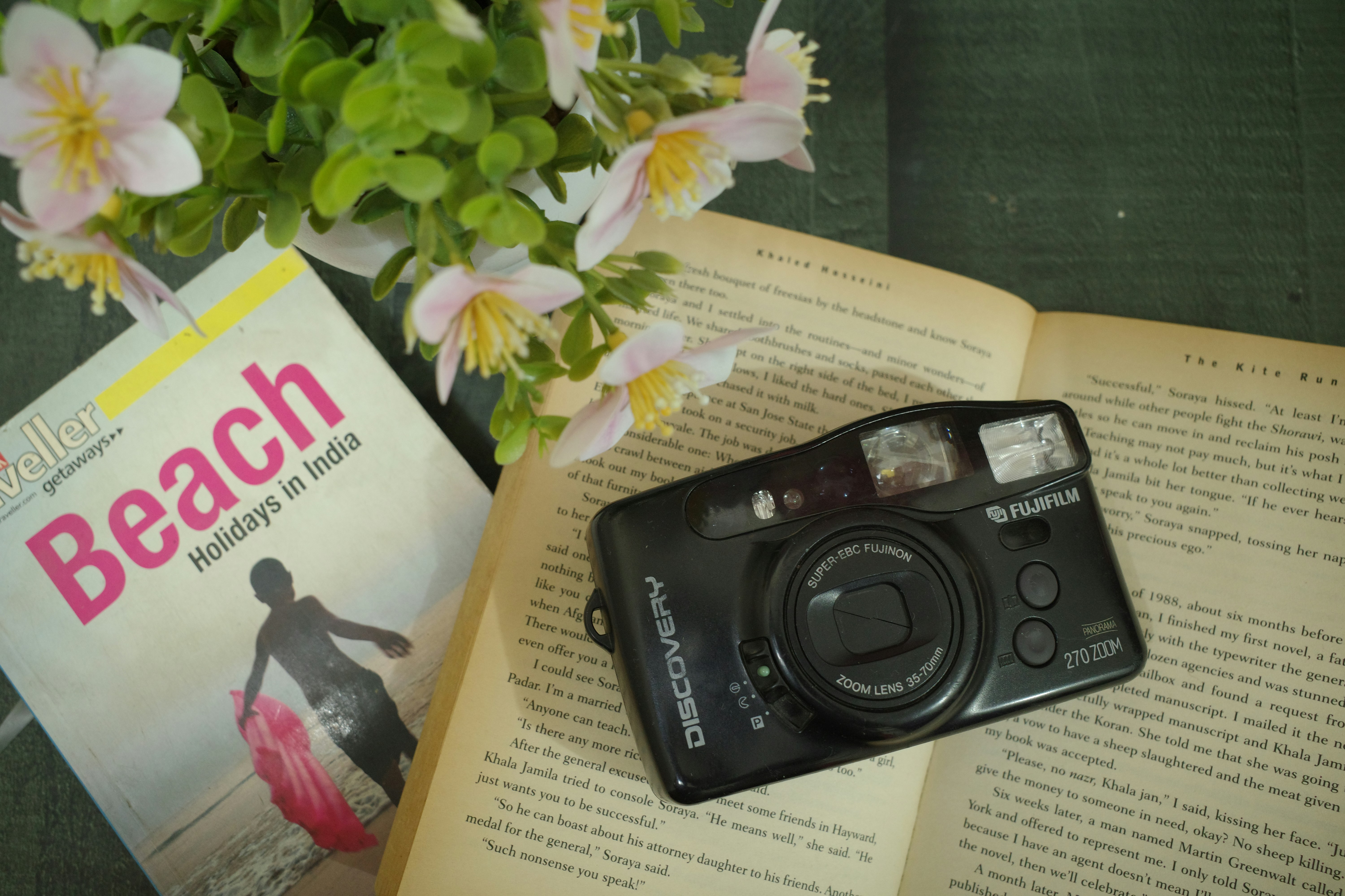 Camera on open book with flowers and beach magazine