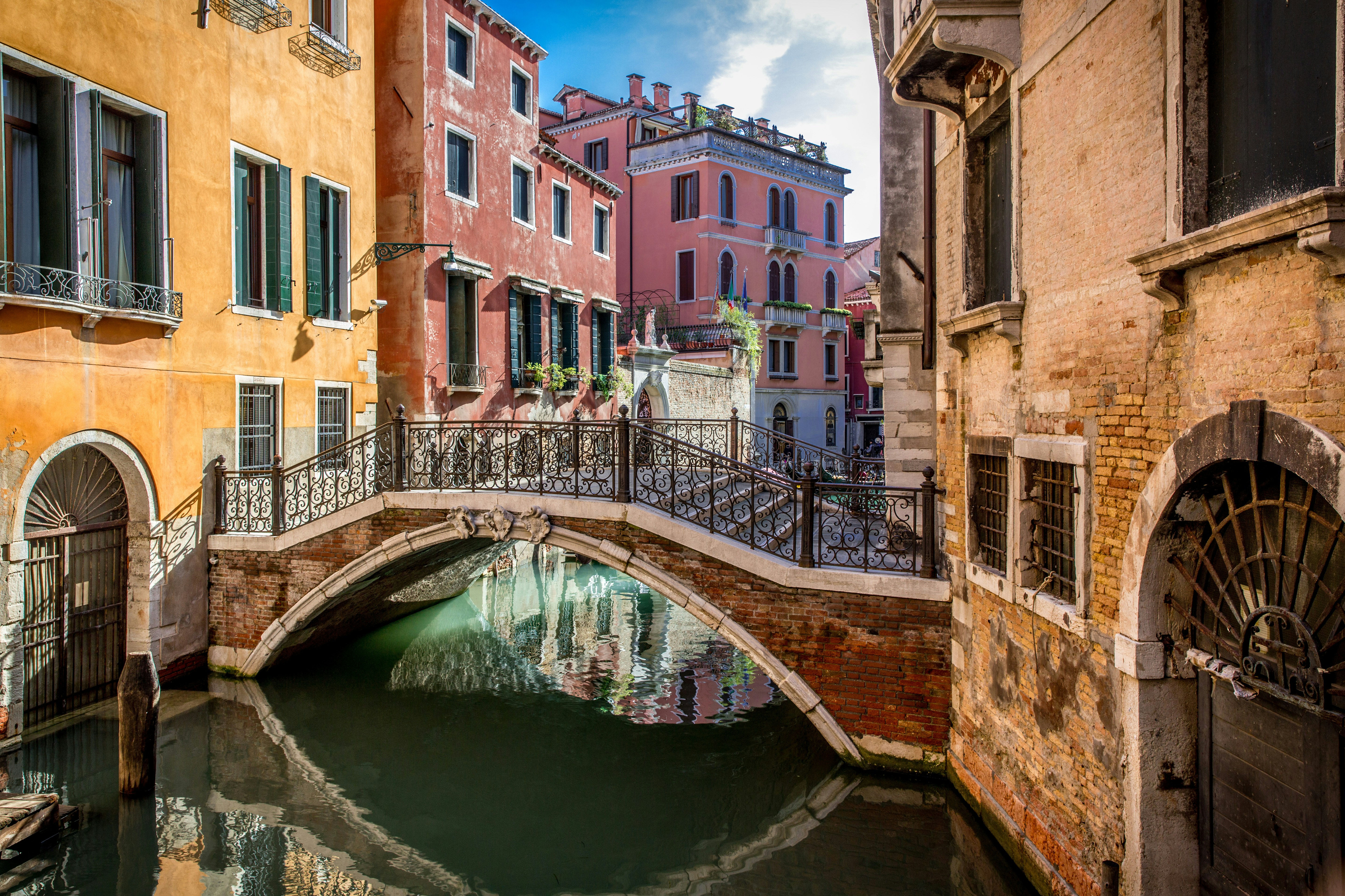 Edifícios coloridos margeiam um canal com uma ponte em Veneza.
