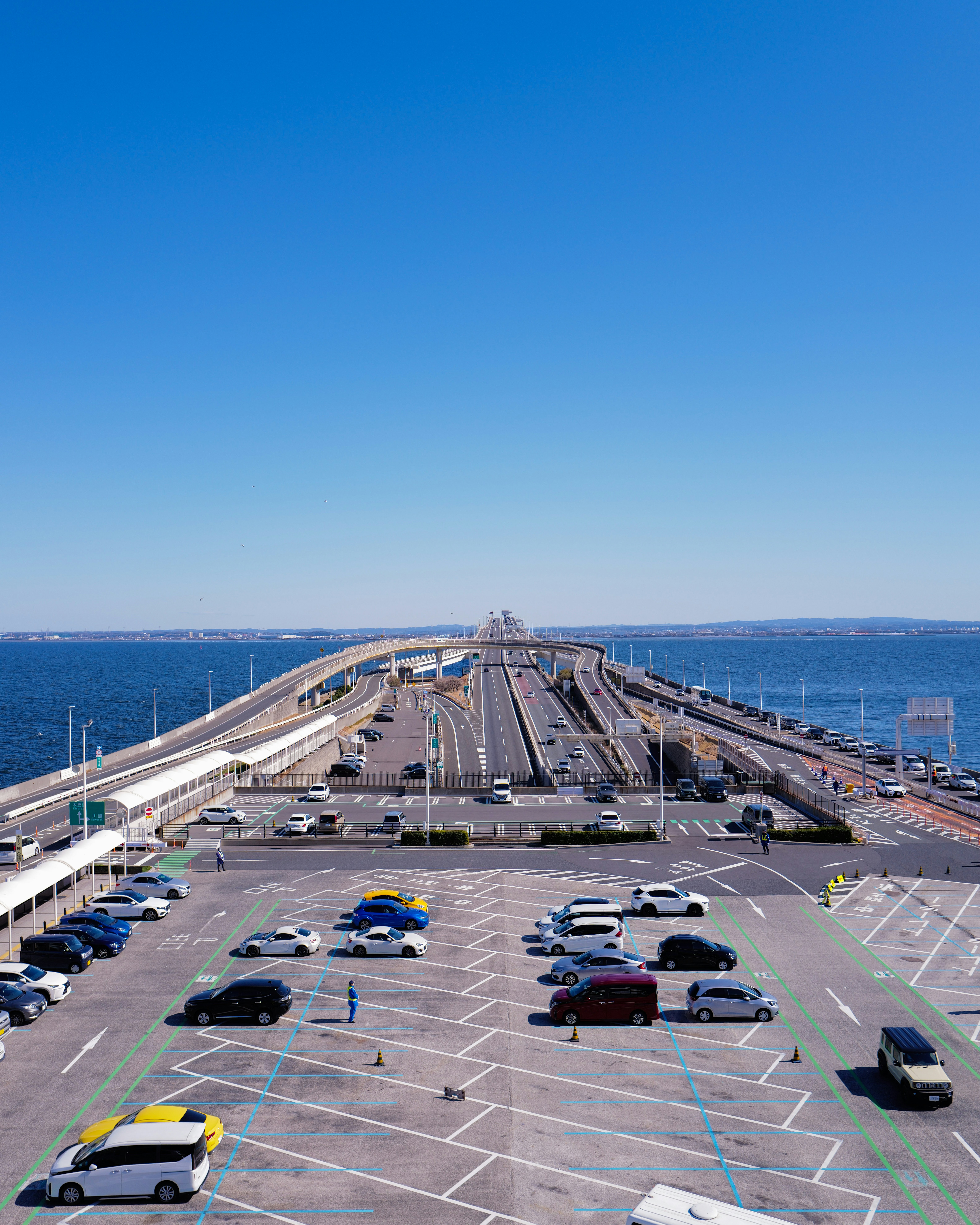 Cars on a long bridge over blue water