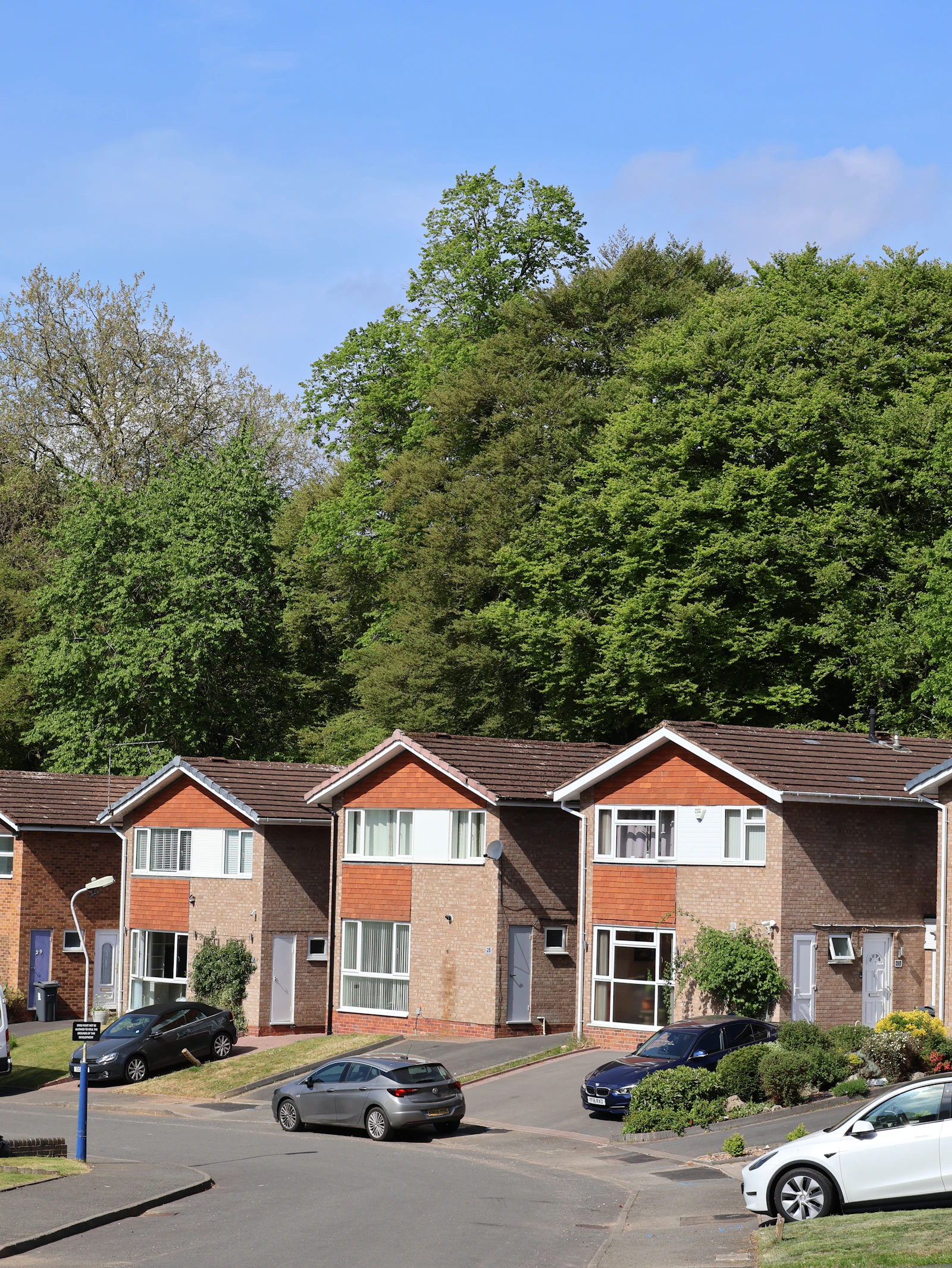 Row of brick residential homes with cars parked along the street