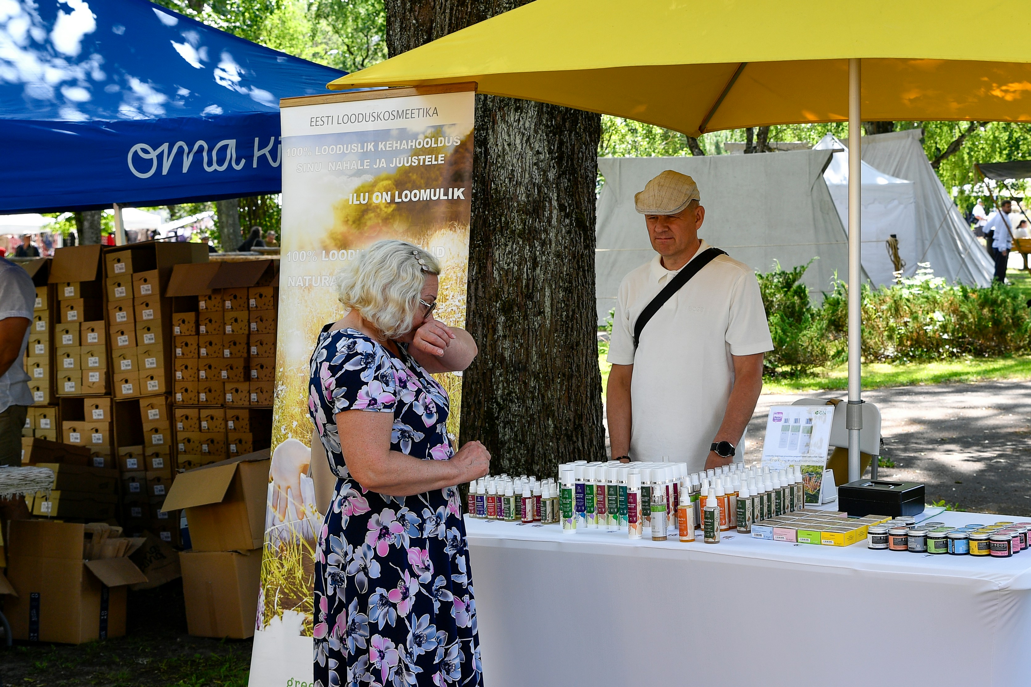 Femme qui regarde des produits à un stand de marché en plein air.