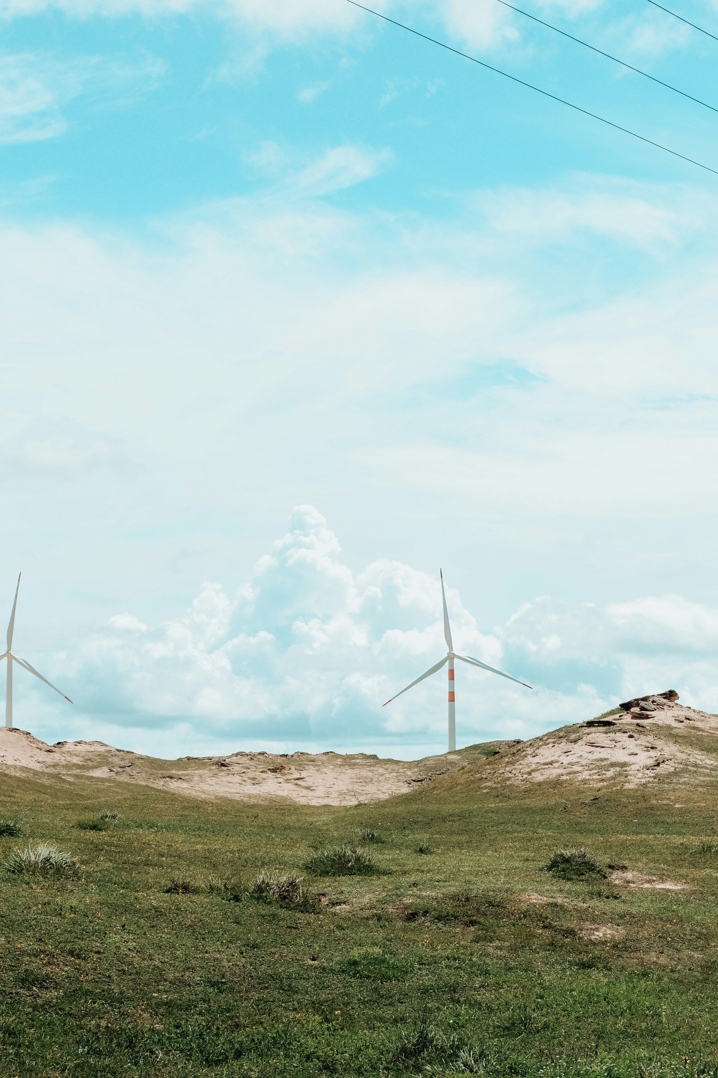 Éoliennes sur une colline herbeuse sous un ciel nuageux