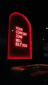 Red neon sign reads "your comfort zone will kill you".