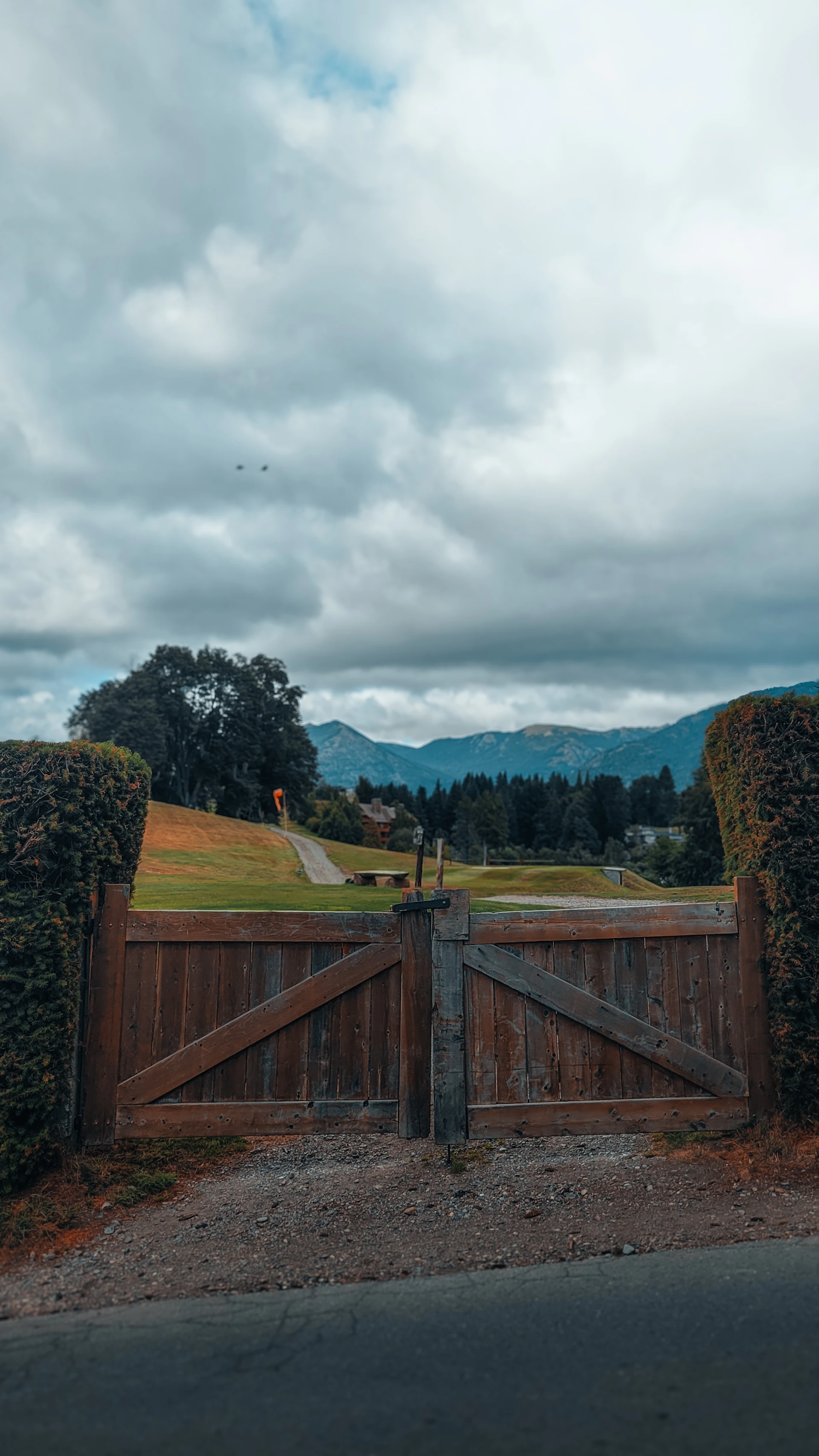 Wooden gate opens to a green landscape and mountains.