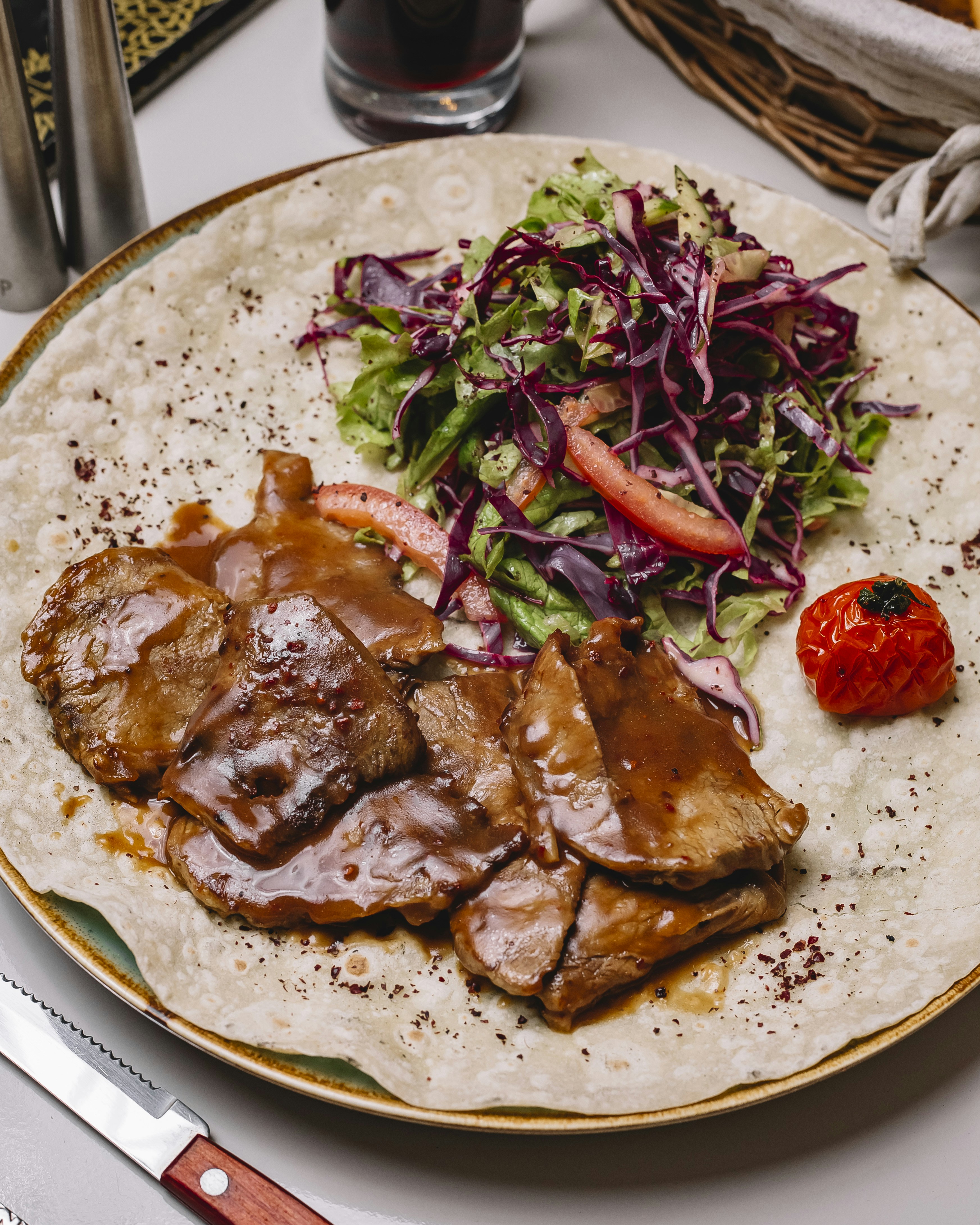 Thinly sliced meat with sauce and salad on flatbread.