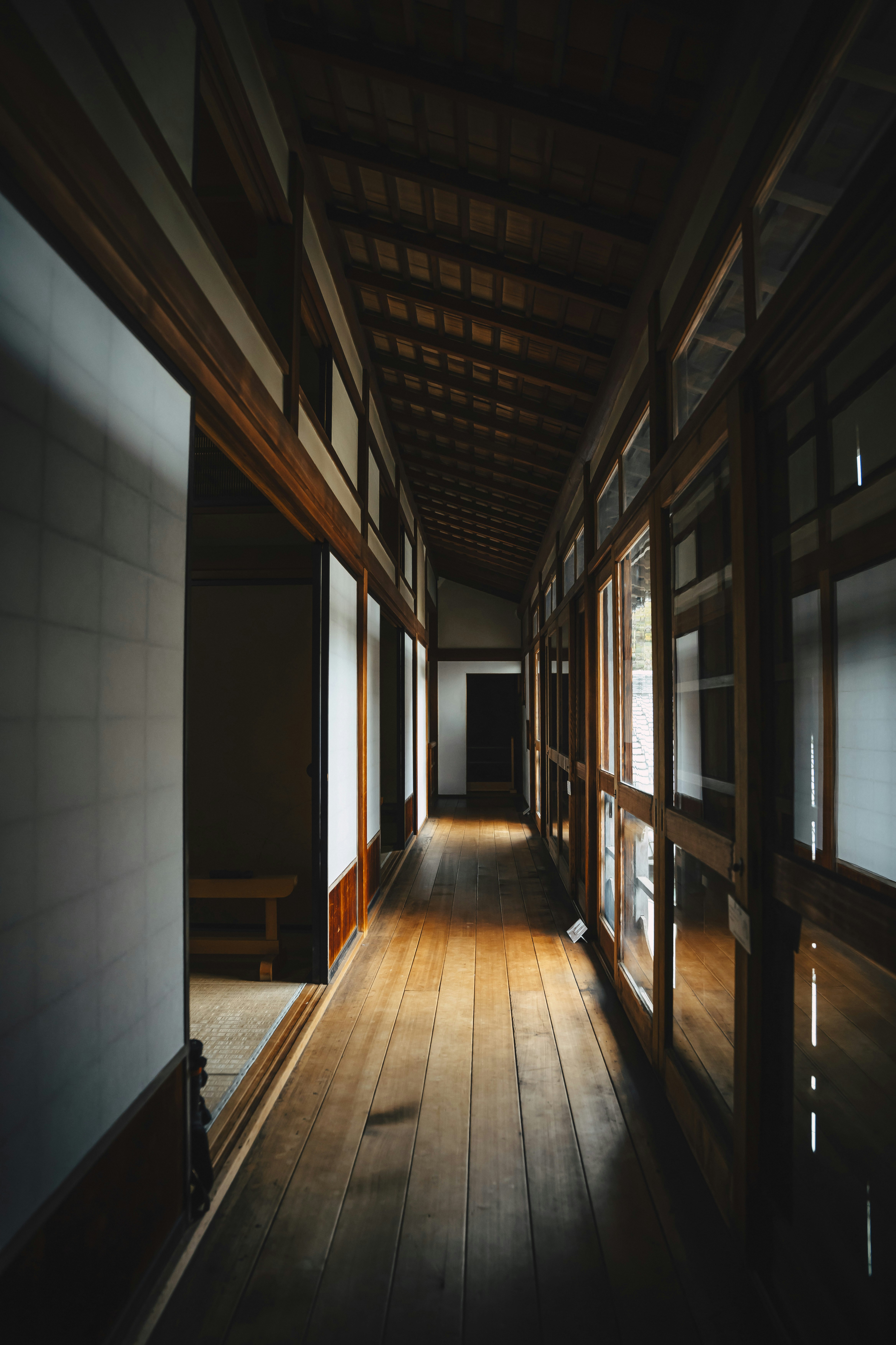 Sunlight streams down a wooden hallway in an old building.