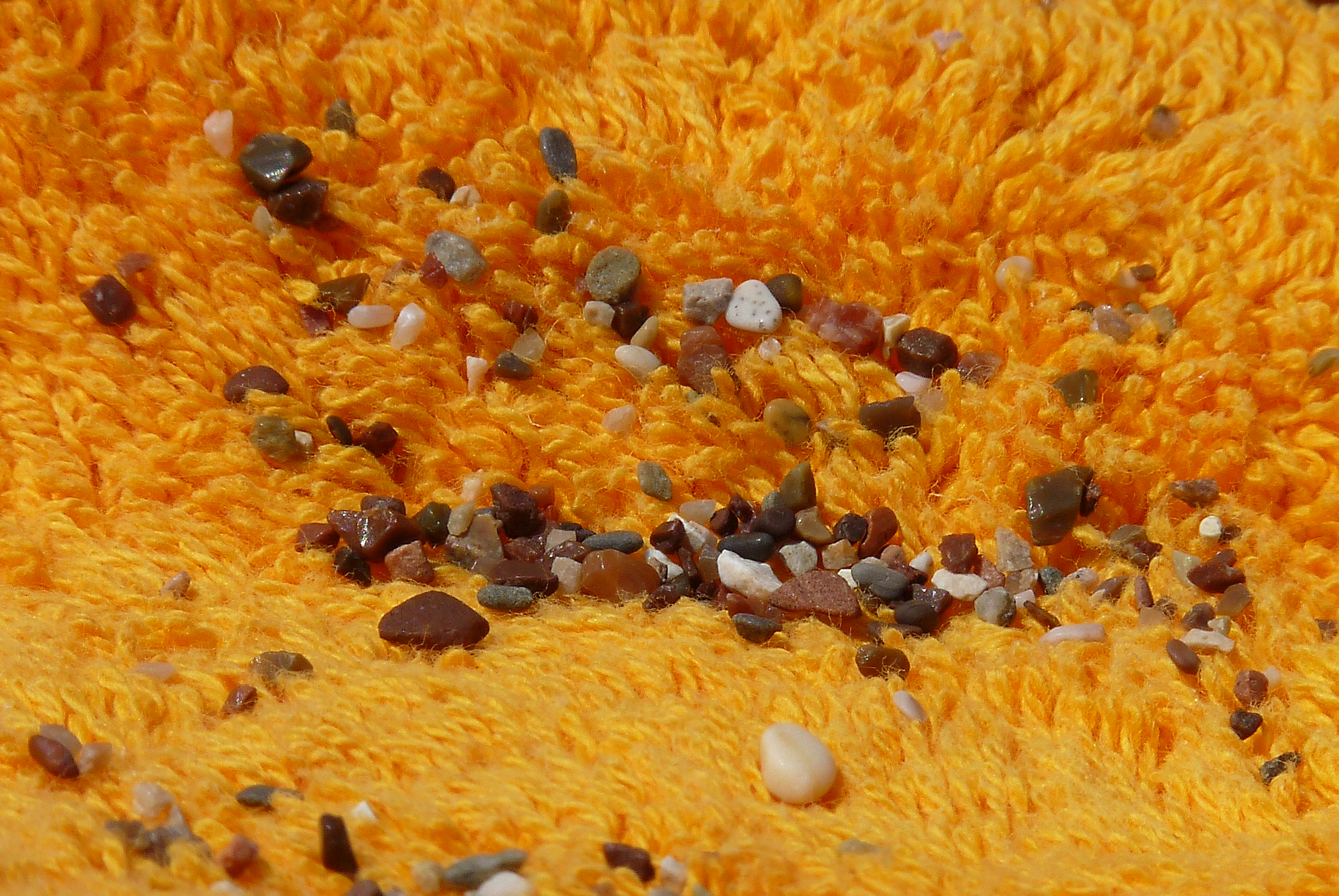 Small pebbles scattered on an orange textured surface.