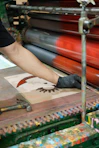 Artist applies ink to printing plate with gloved hand