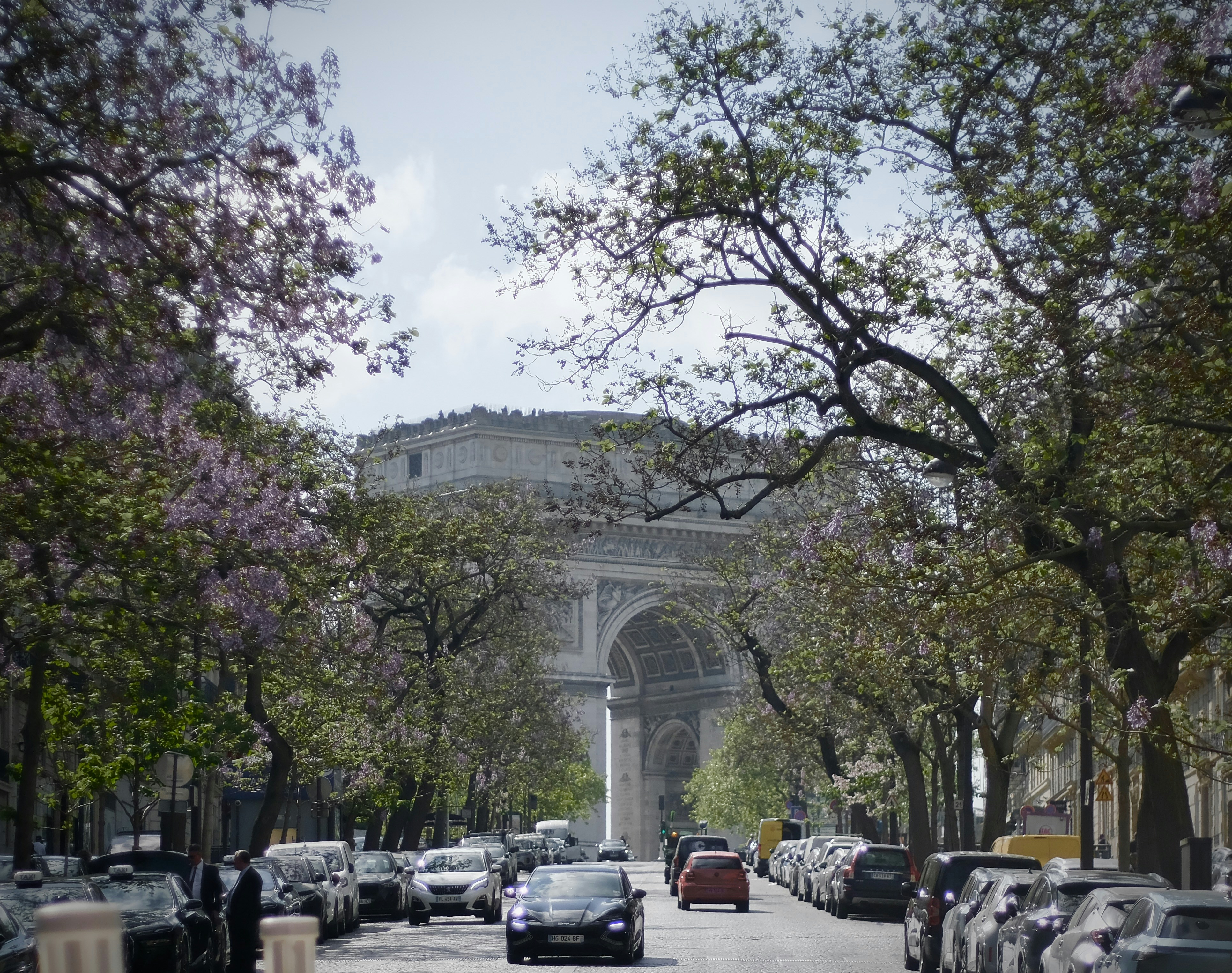 Arc de triomphe seen from a tree-lined street.