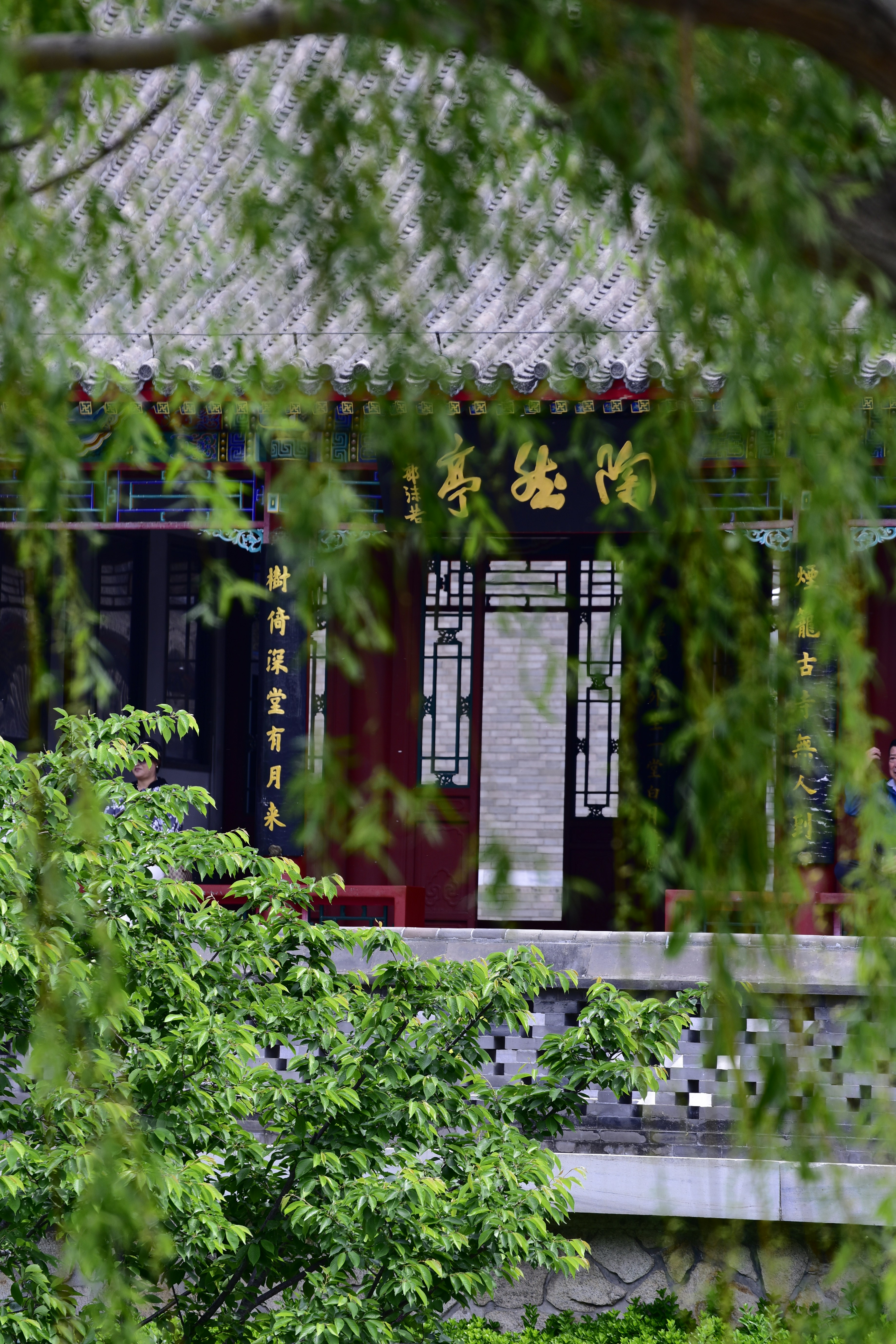 Bâtiment chinois traditionnel avec des détails ornés et de la verdure.