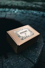 Cardboard box with floral label on stone surface