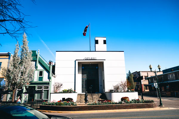 A modern white municipal building with a flag mounted at the top — Cedar Mill City Hall