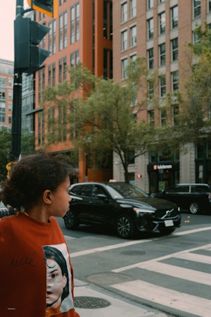 A child waiting at a crosswalk on a city street, the moment traffic gardens help kids practice for