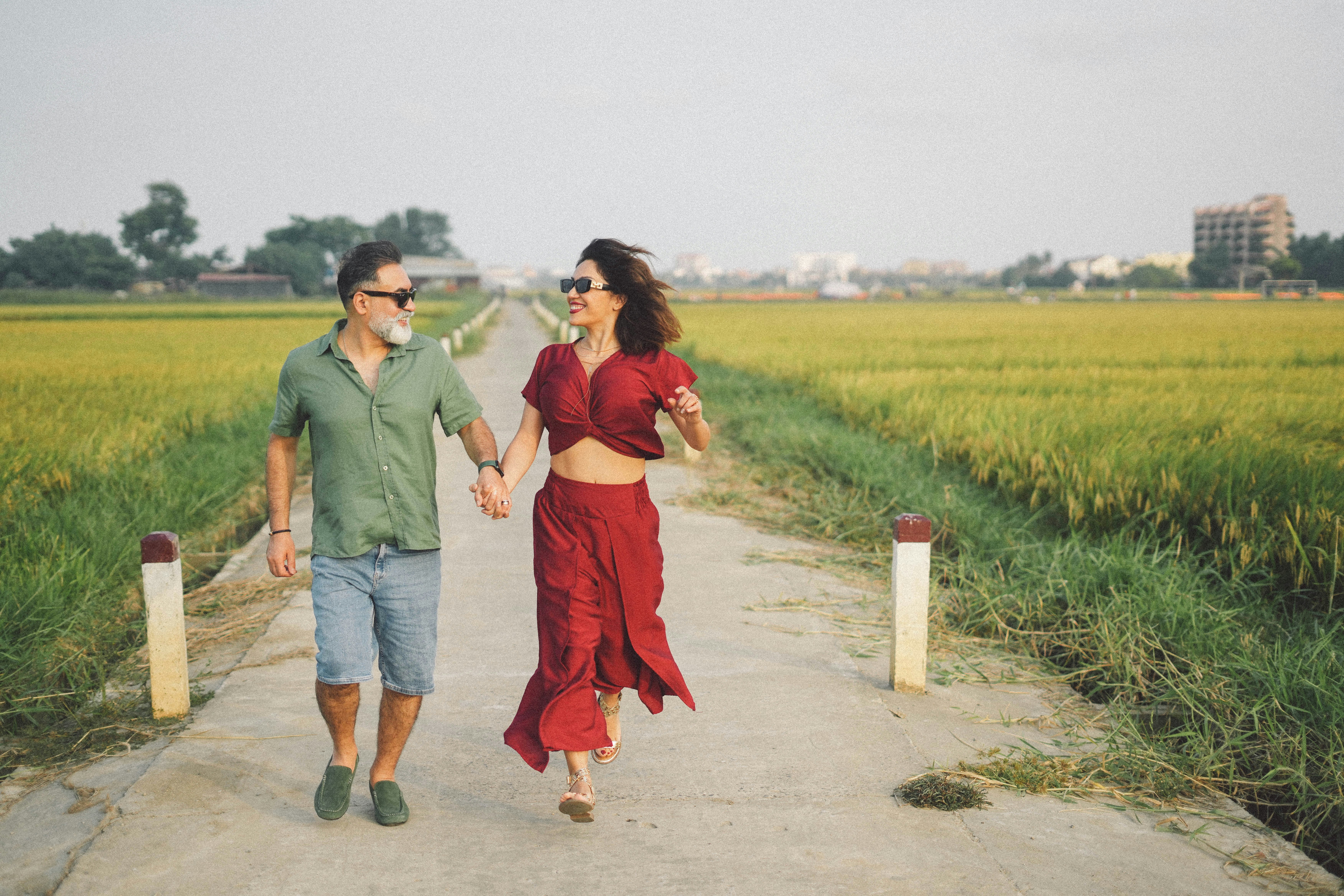 Pareja caminando de la mano por un paisaje rural.