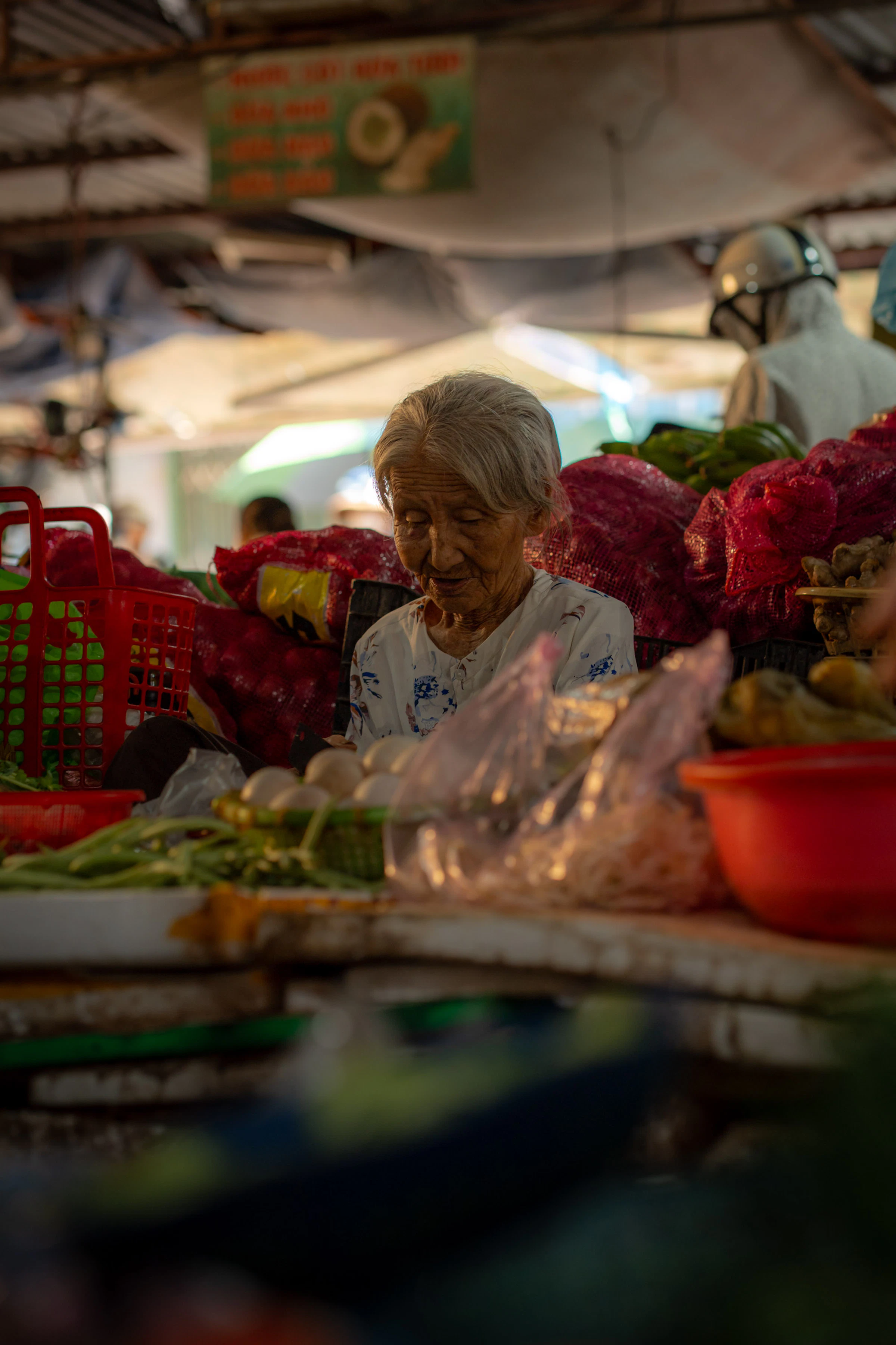 Elderly woman at a market stall with produce