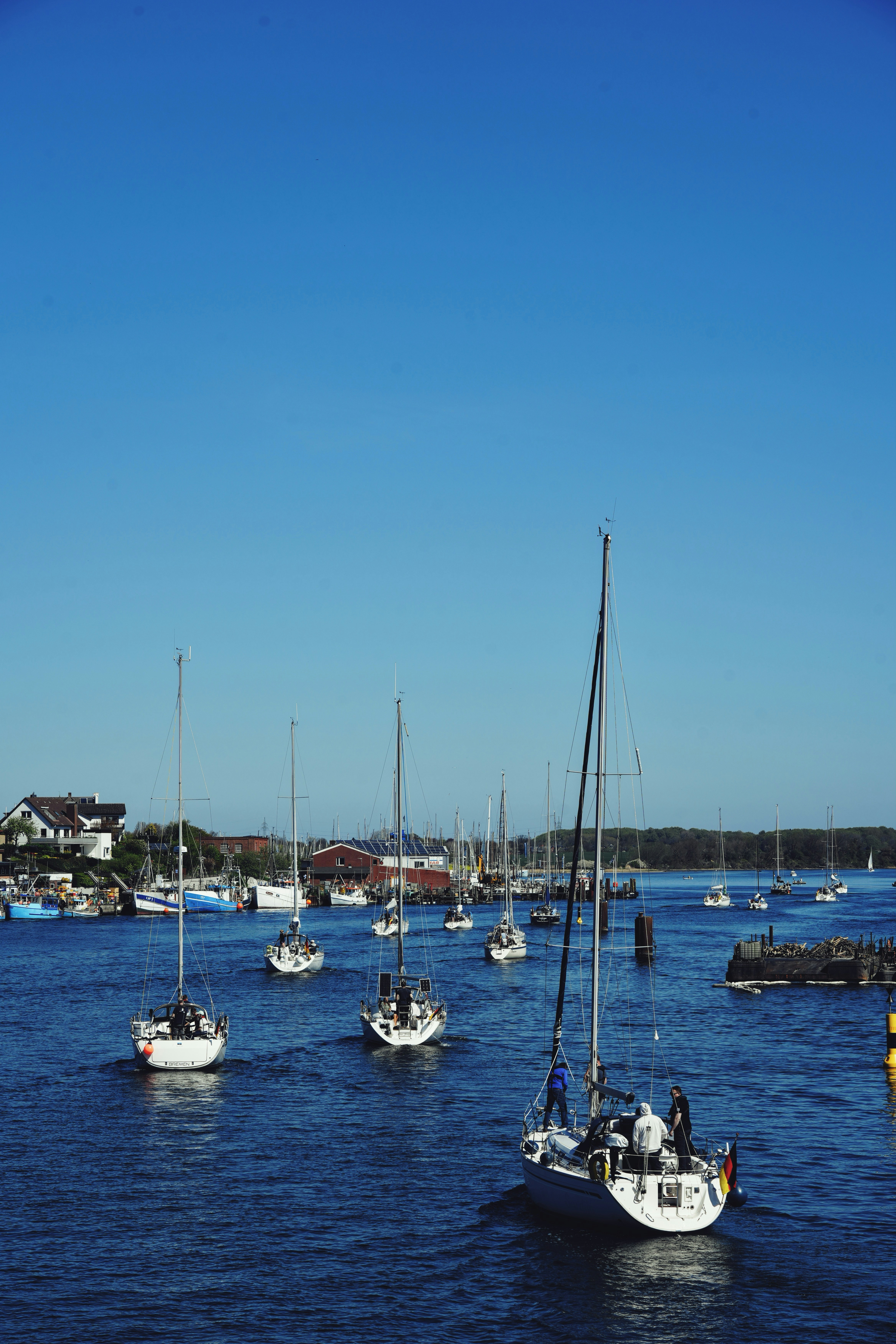 Des voiliers naviguent dans un port bleu clair sous un ciel éclatant.