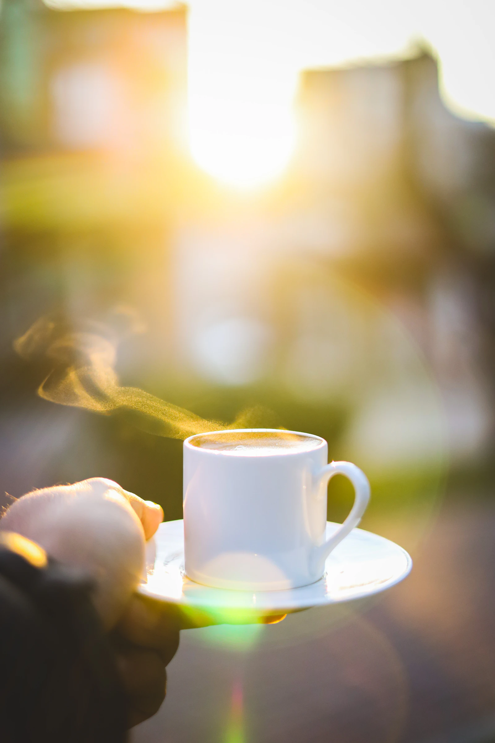 Dampfende Kaffeetasse in der Hand im warmen Licht eines neuen rauchfreien Morgens