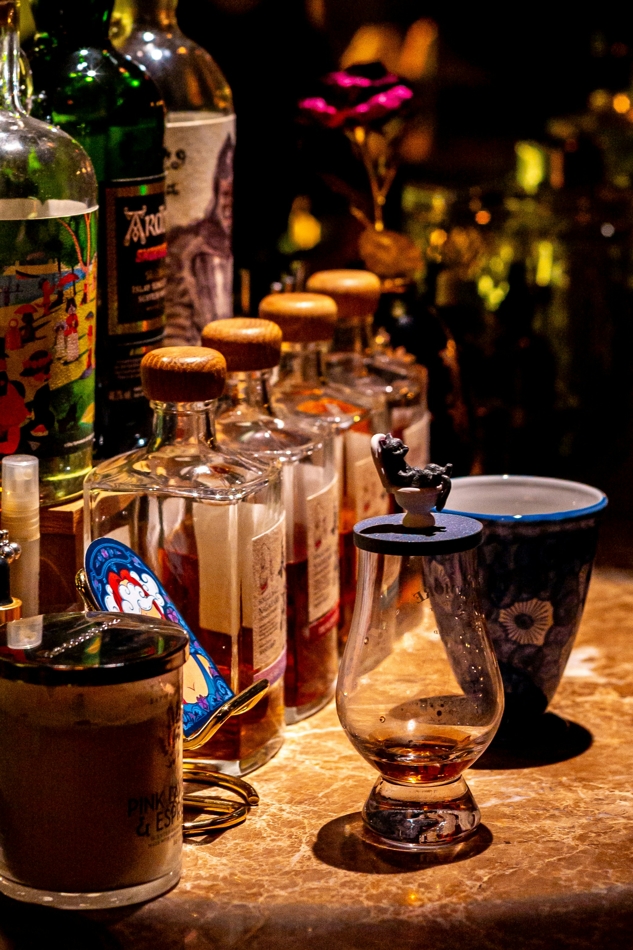 Premium spirits bottles and a tasting glass in a dark bar setting