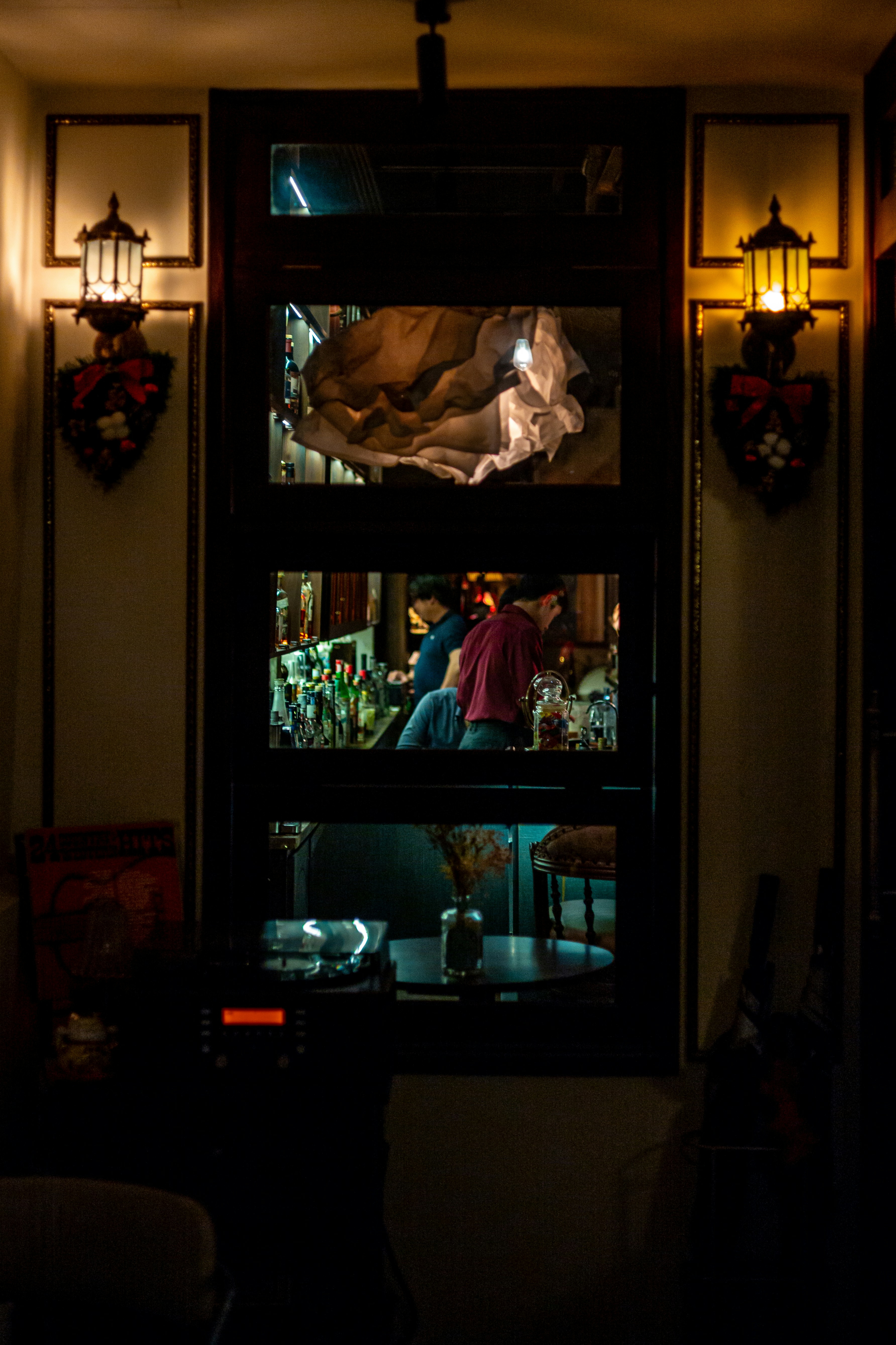 Blick durch ein Fenster einer Bar mit Gästen.