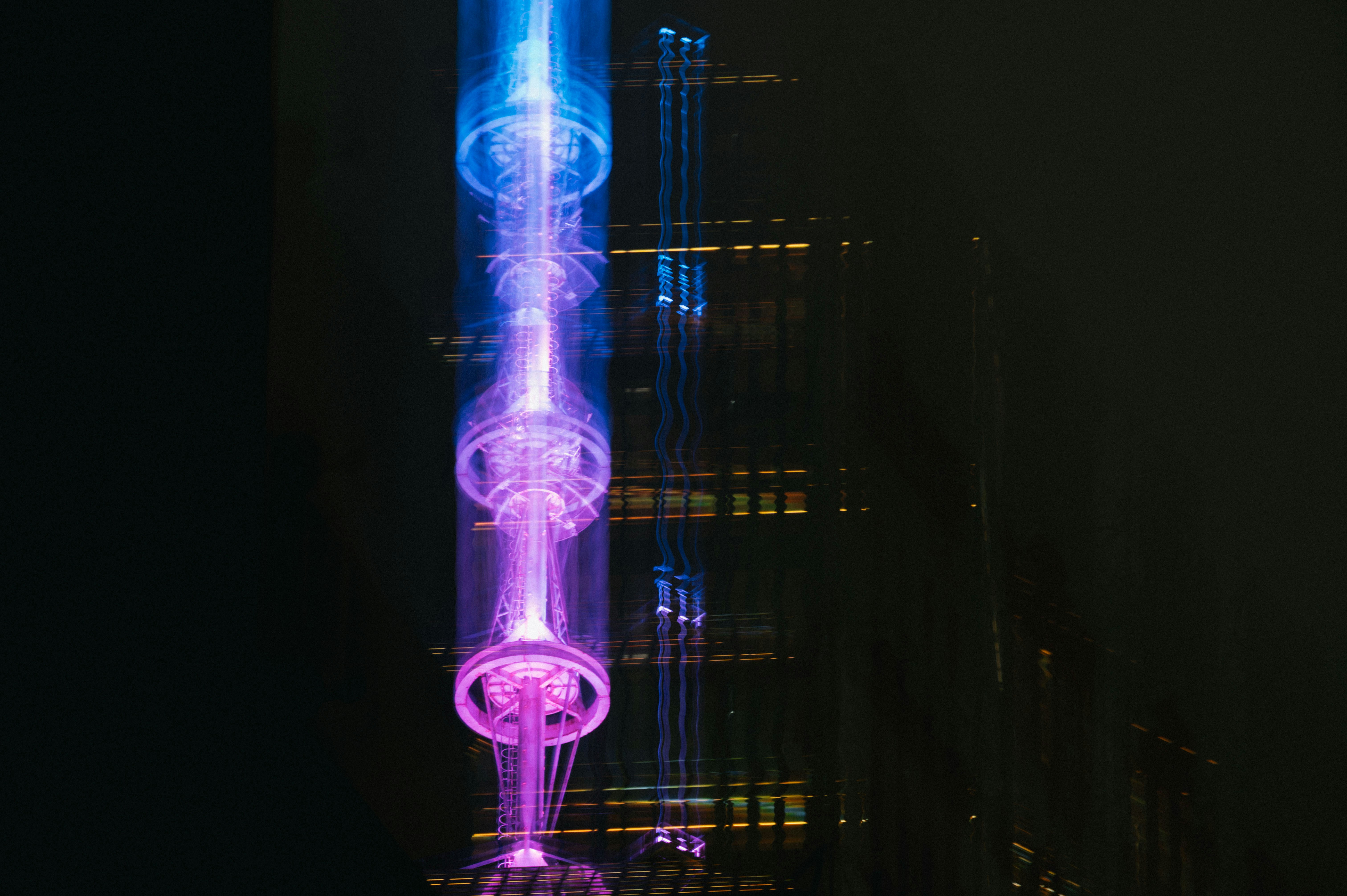 Tall building with purple and blue lights at night.