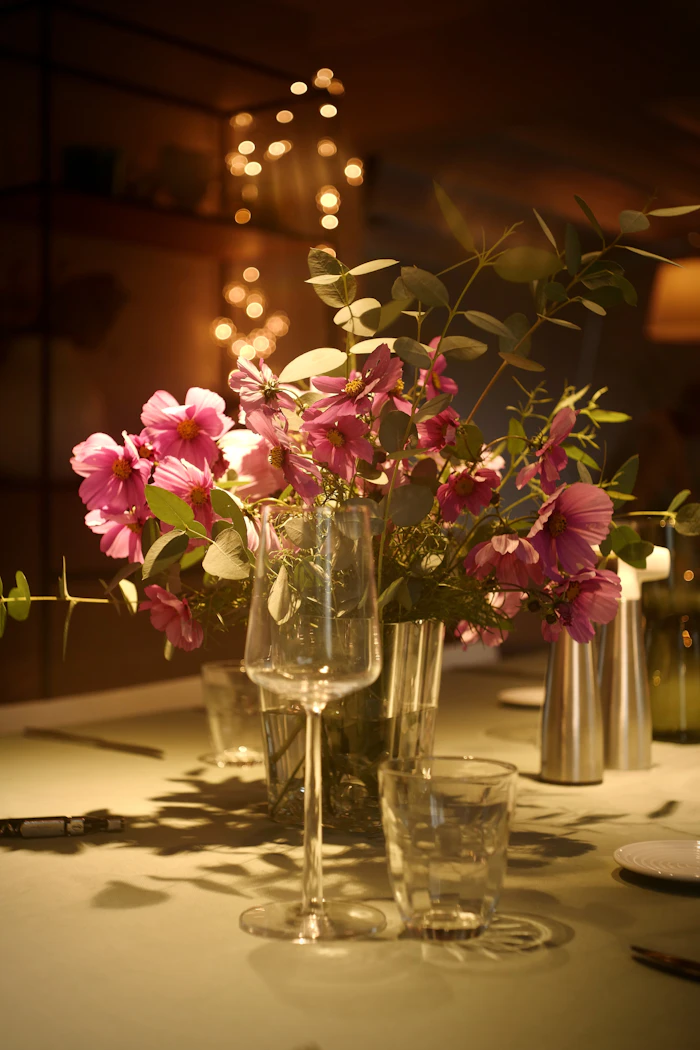 Flores rosas y copas de vino sobre la mesa