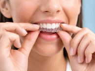 Woman adjusting clear dental aligners on teeth