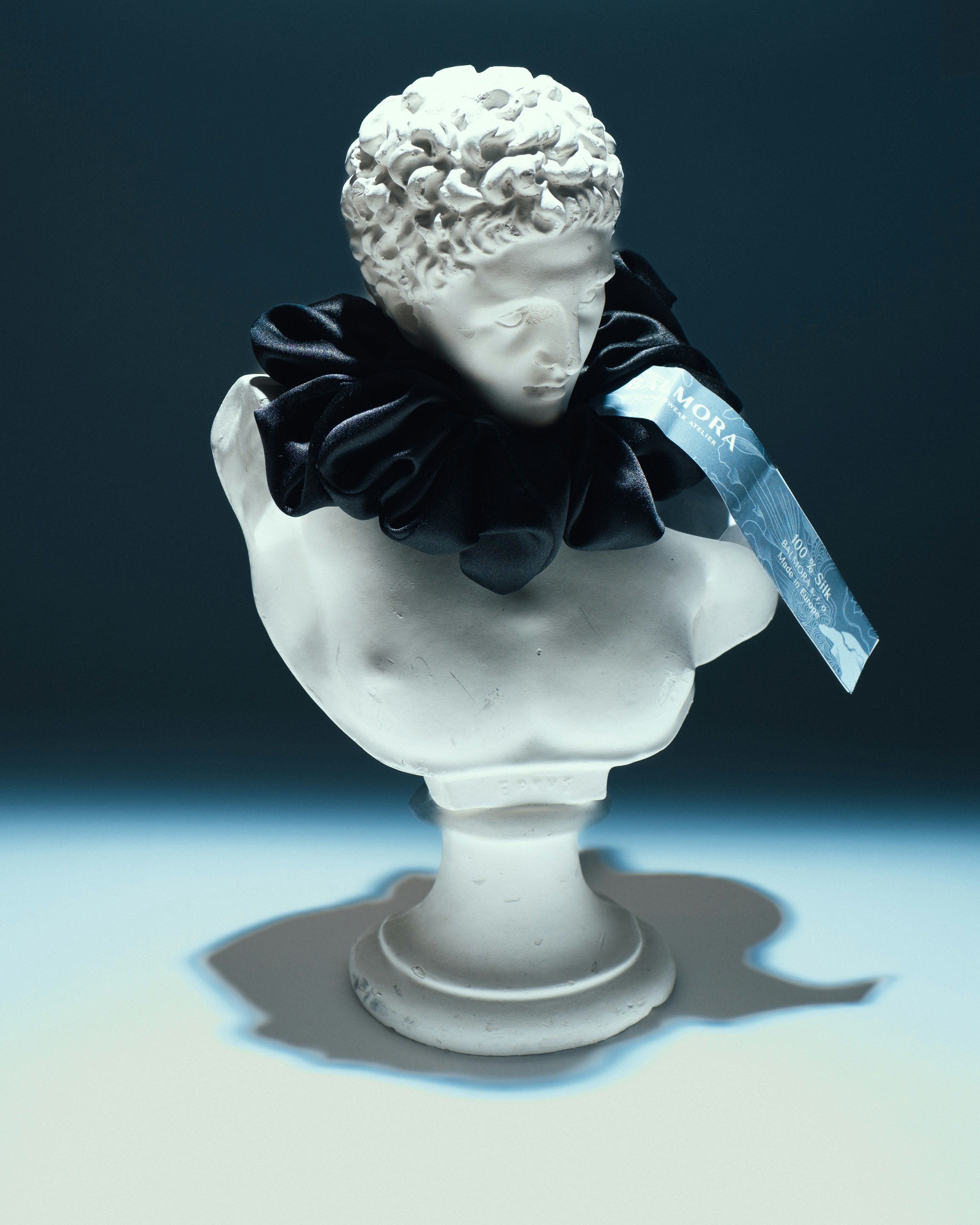 Busto de mármore branco com gola preta com babados e etiqueta