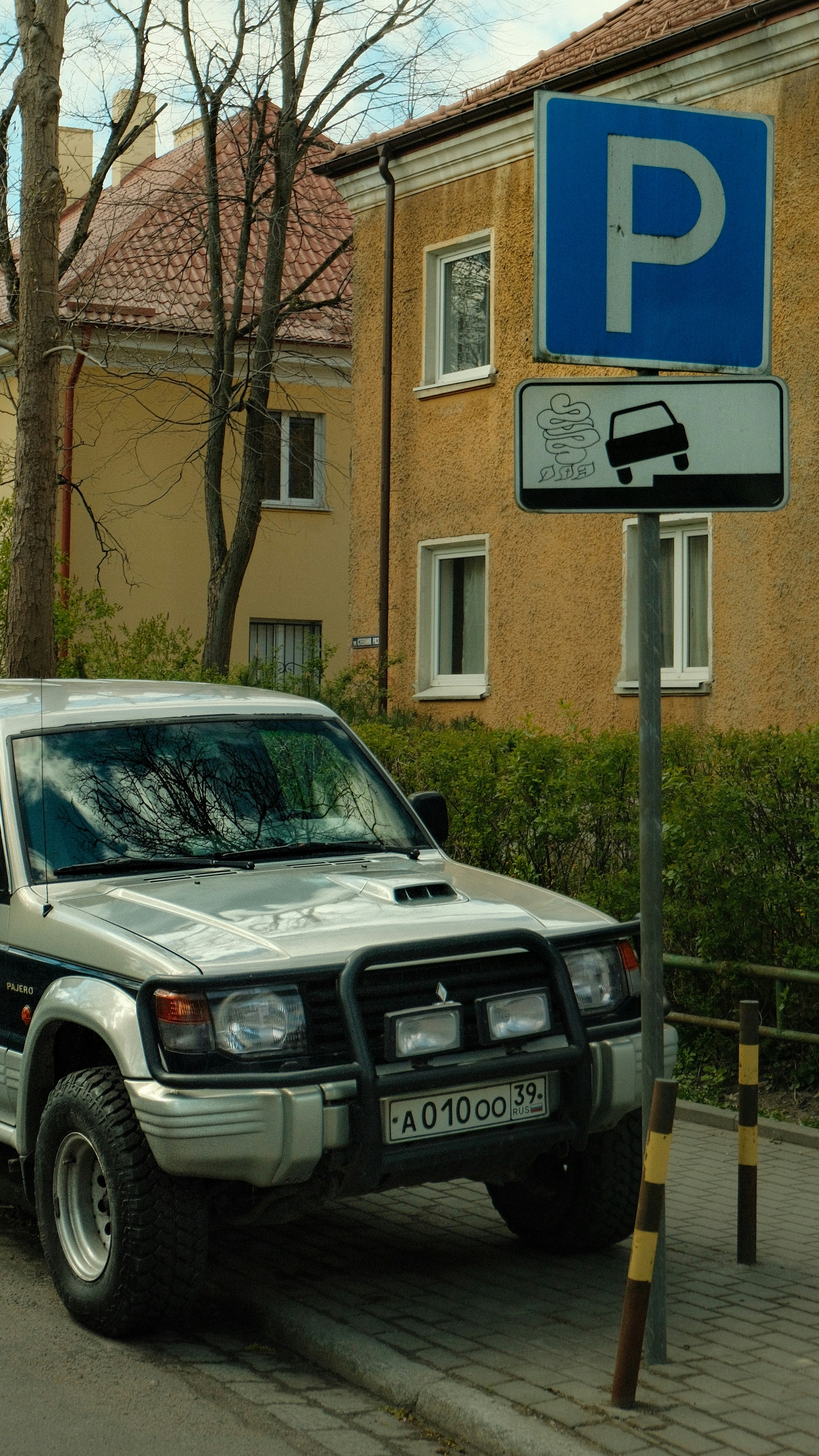 シルバーのSUVが駐車標識のある建物の近くに停まっている。