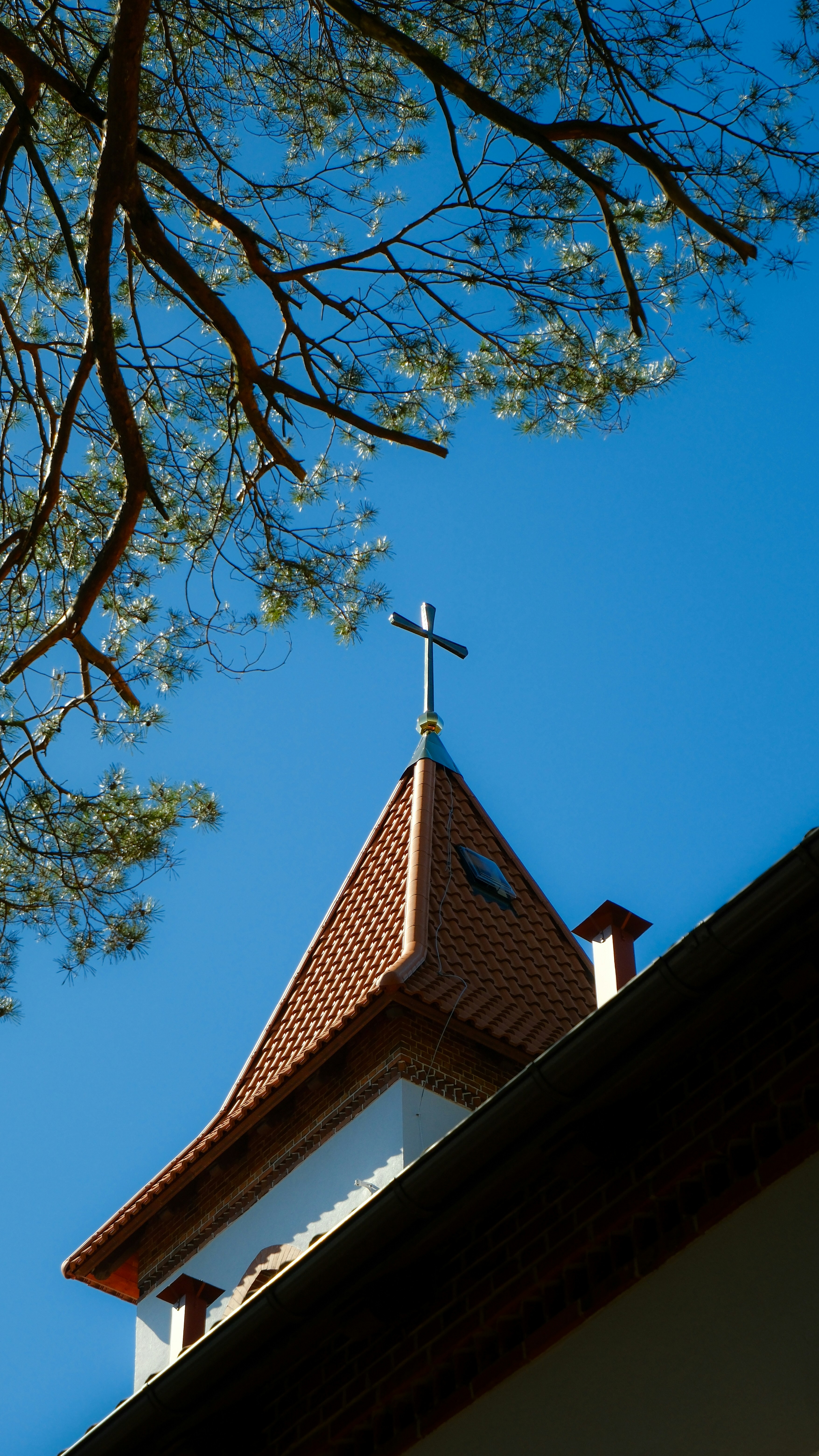 Church steeple with cross against a clear blue sky.
