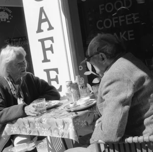 Casal de idosos conversando à mesa de um café