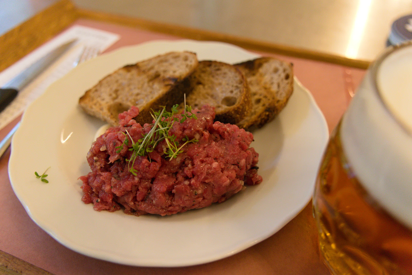 Beef tartare kiểu Âu với bánh mì nướng và bia, so sánh với yukhoe Hàn Quốc