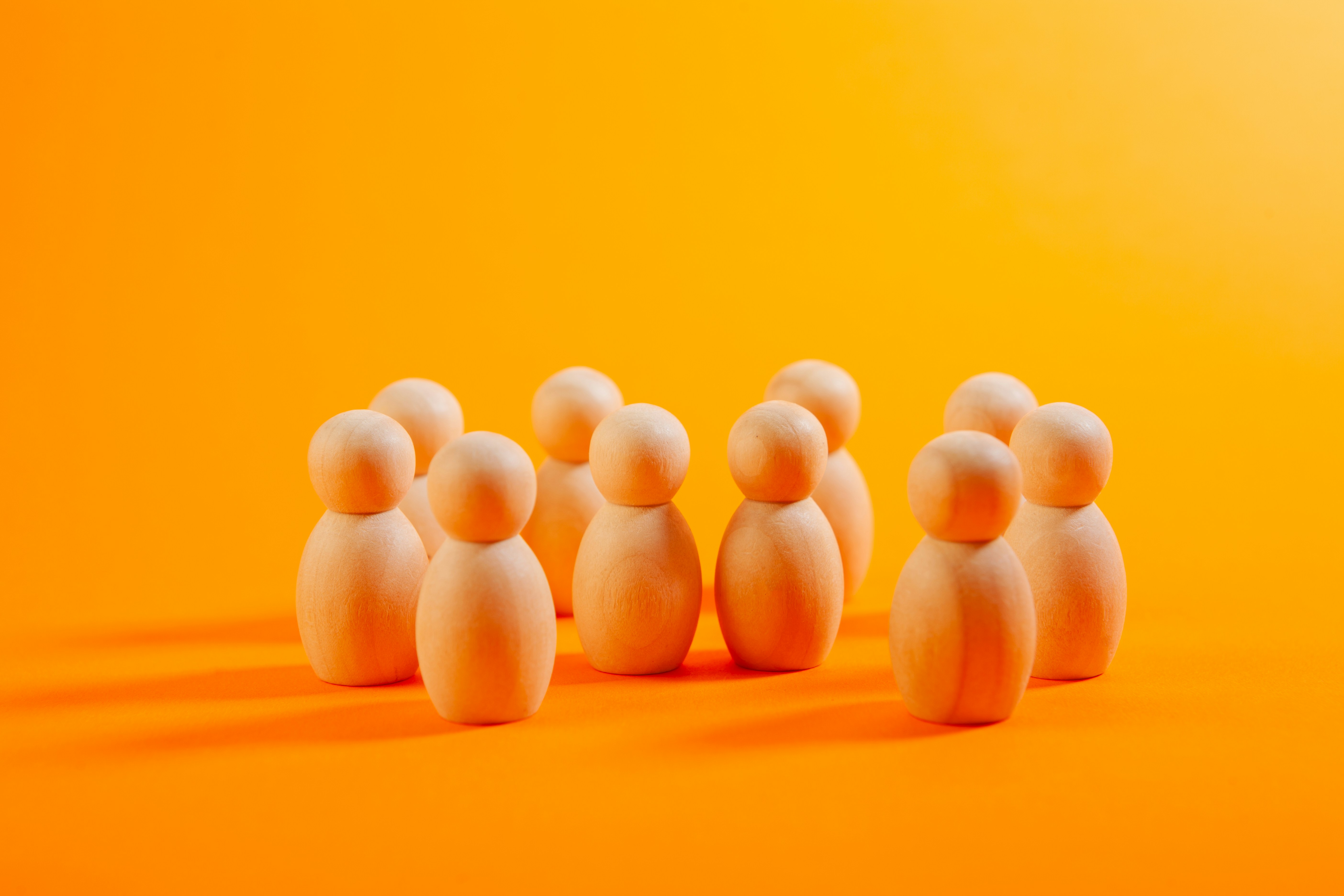 Group of wooden peg people on orange background