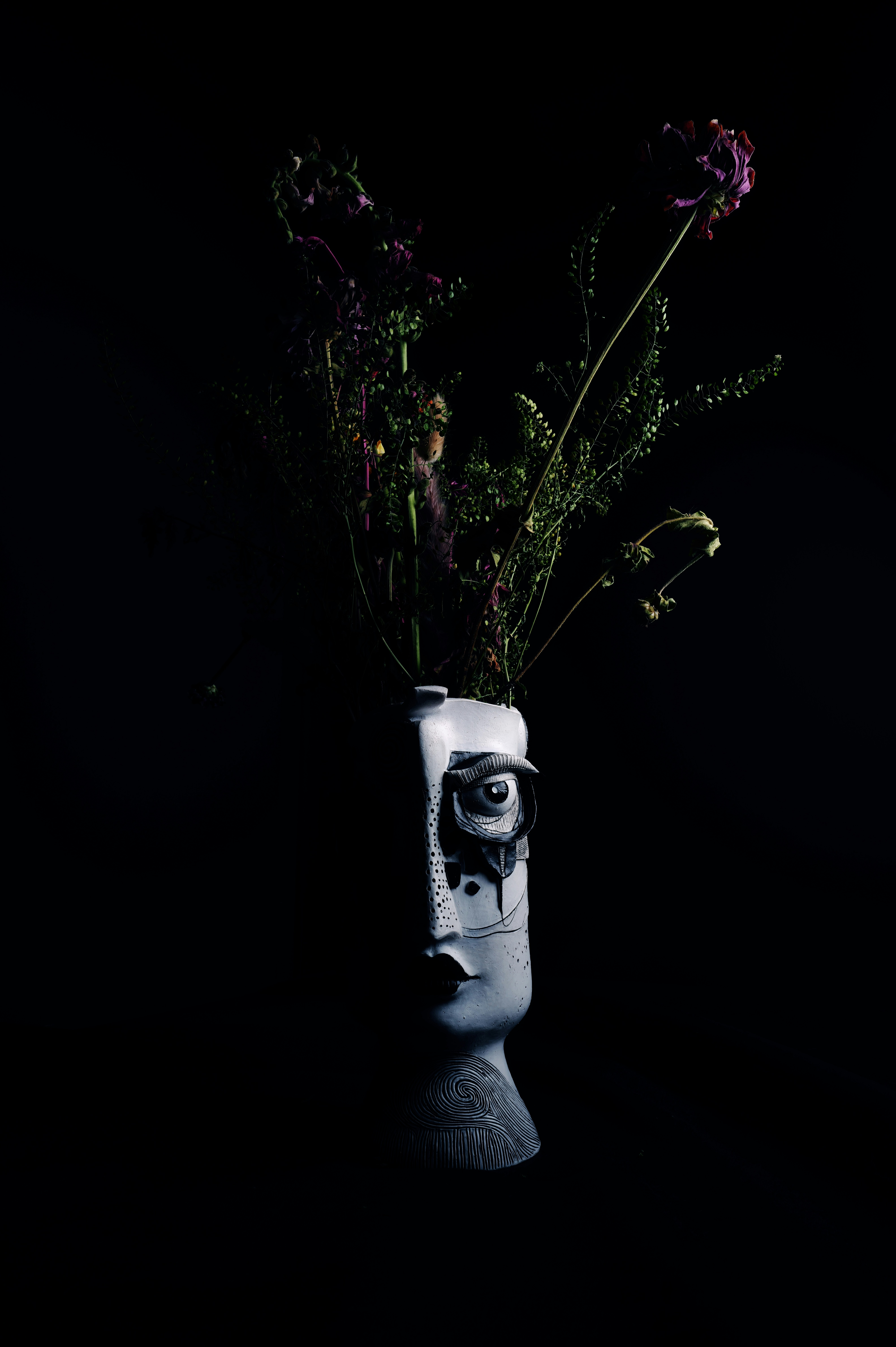 Vase sculptural avec des fleurs séchées sur fond noir